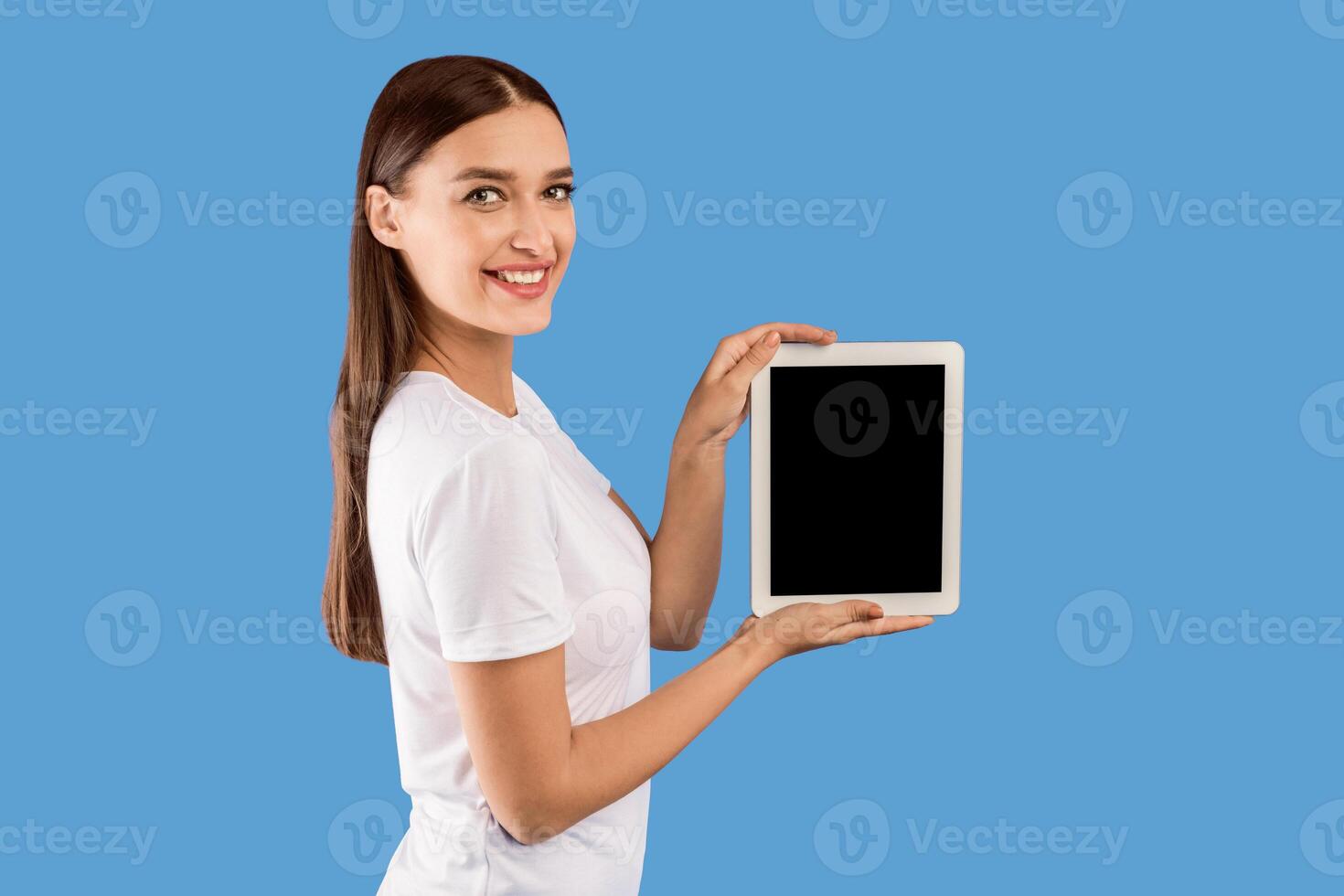 Cool Application Concept. Smiling woman holding tablet, showing black blank screen, empty space, mock up photo