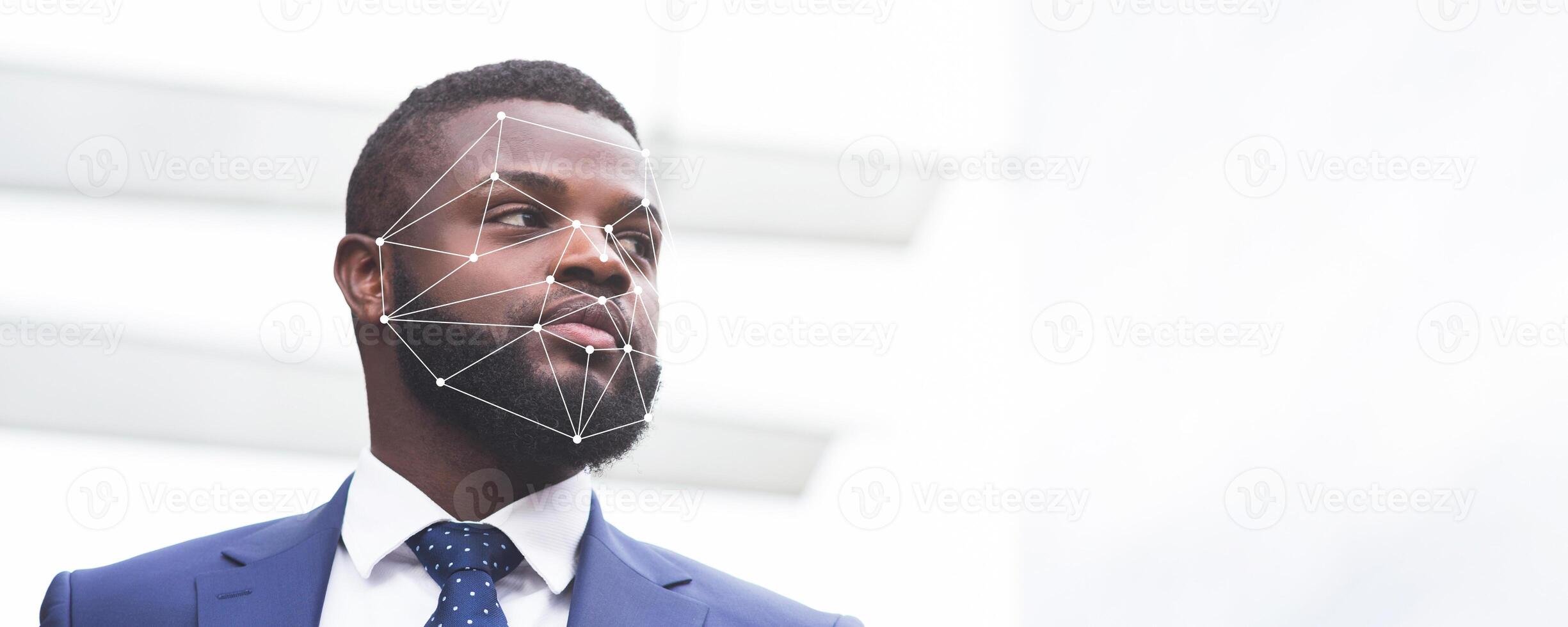 A man in a blue suit stands confidently, with a facial recognition overlay superimposed on his face. This advanced technology highlights the growing use of ID verification in various environments. photo
