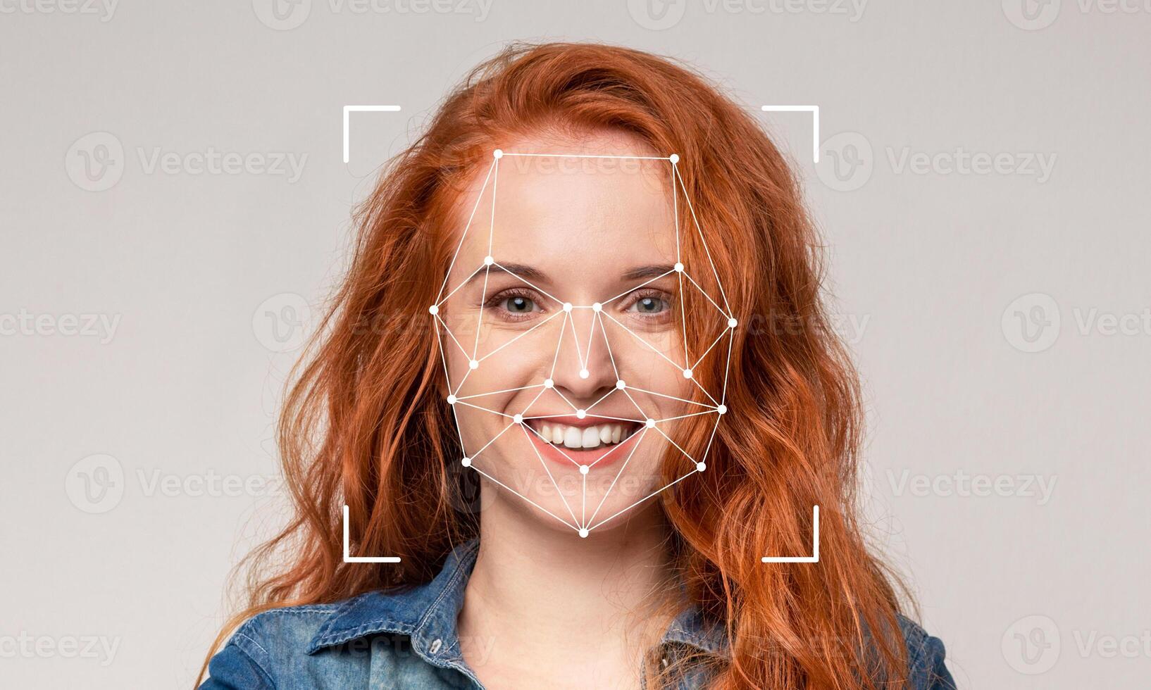 A smiling person with red hair is displayed against a plain background while facial recognition technology identifies features. The setting is neutral without specific details or distractions. photo