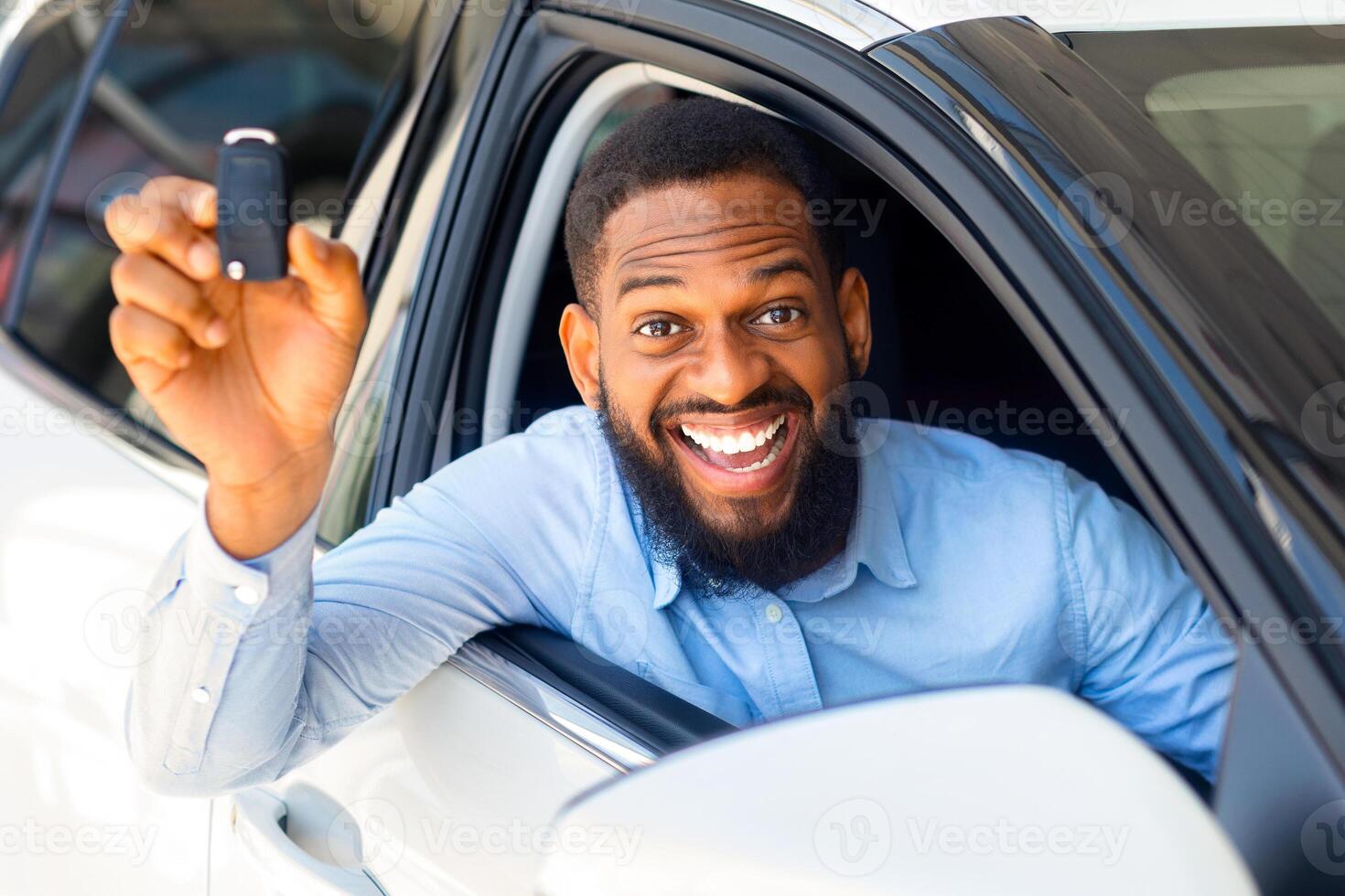 Happy Black Man Sitting In New Car, Holding Key And Smiling At Camera, Joyful African American Male Celebrating Purchasing New Automobile, Bought Vehicle In Dealership Center, Closeup Shot photo