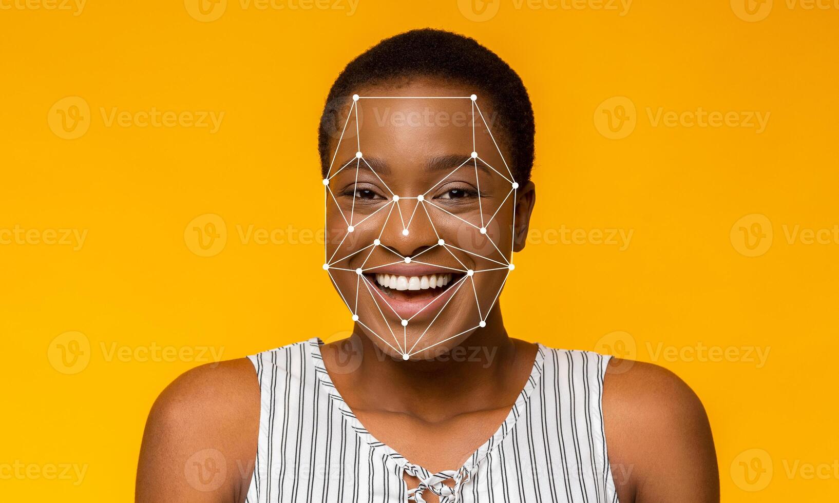 A woman with short hair is smiling while facial recognition technology outlines her features. The bright yellow background enhances the focus on her joyful expression and the tech overlay. photo