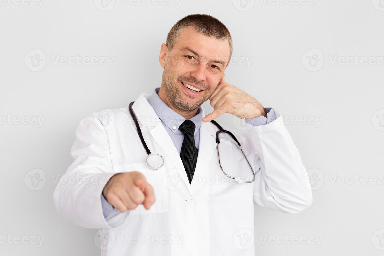 Better Call Doctor. Portrait of mature smiling male doctor showing call me gesture isolated over white background photo