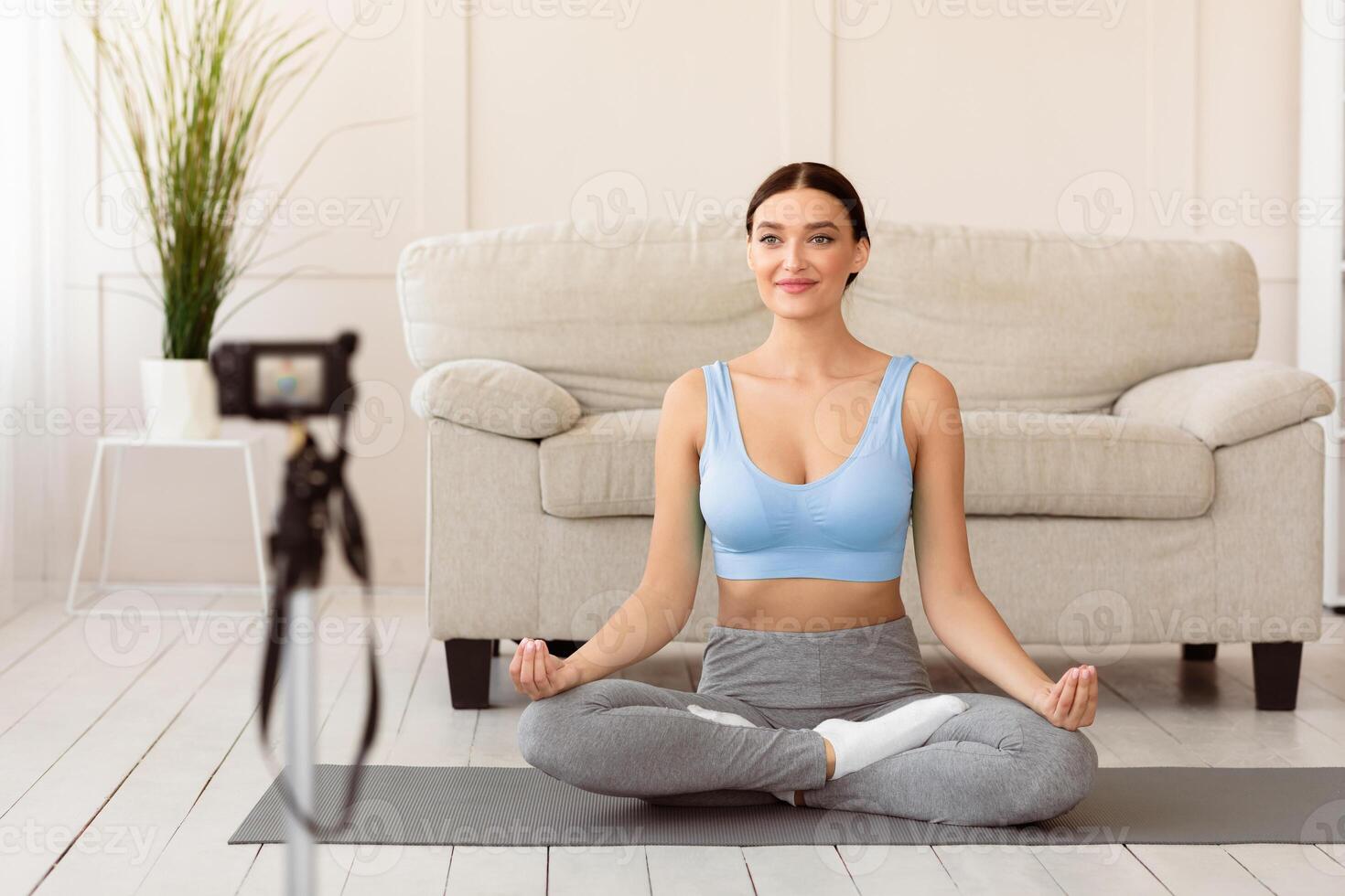 Online Meditation. Yoga Blogger Woman Making Fitness Blog Sitting In Lotus Position On Mat At Home. Selective Focus photo