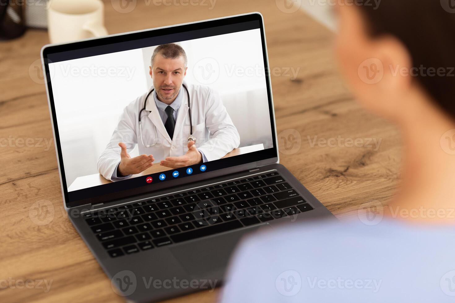 Telemedicine Concept. Back view over the shoulder closeup of woman having online call with doctor on laptop, sitting at home. Professional physician giving remote distance consultation photo