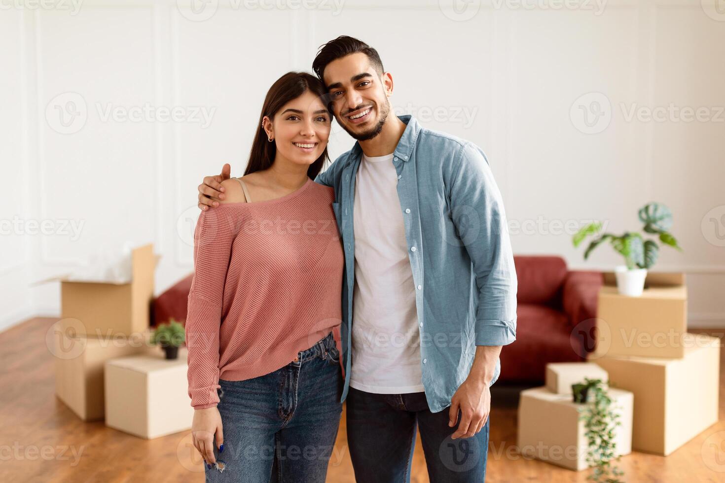 Love, Young Family And New Home. Portrait Of Happy Young Spouses Hugging And Posing Looking At Camera After Moving, Relocating To New Apartment Standing In Living Room. Mortgage And Ownership Concept photo