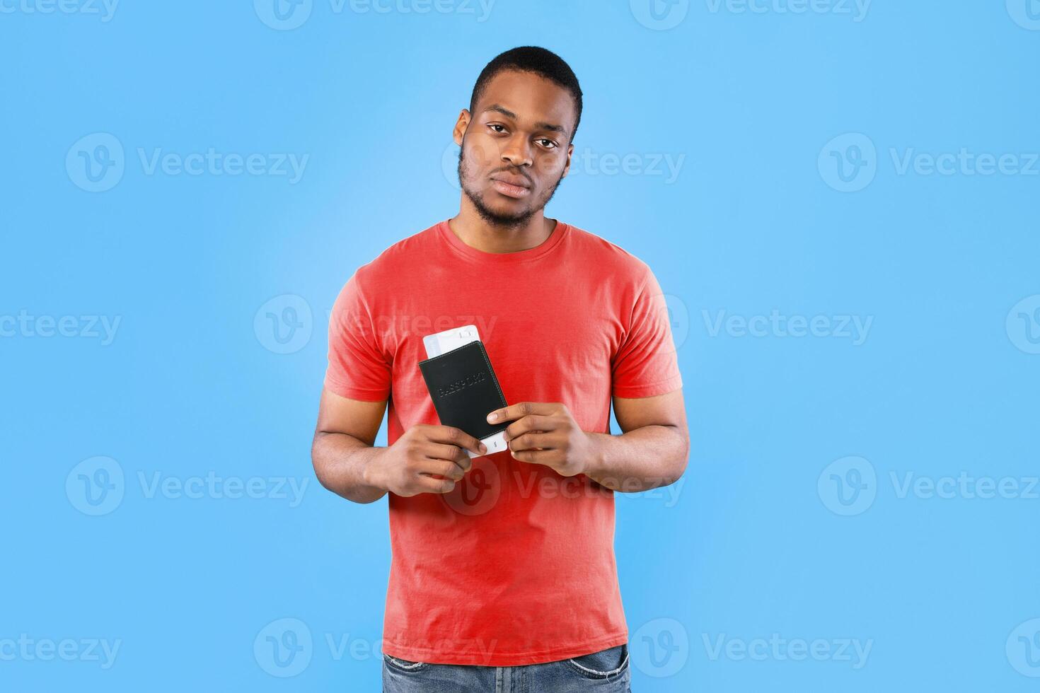 Cancelled Flight. Frustrated Black Traveler Guy Holding Travel Tickets After Cancellation Posing Over Blue Background, Looking At Camera. Tourism Problem During Pandemic Concept photo