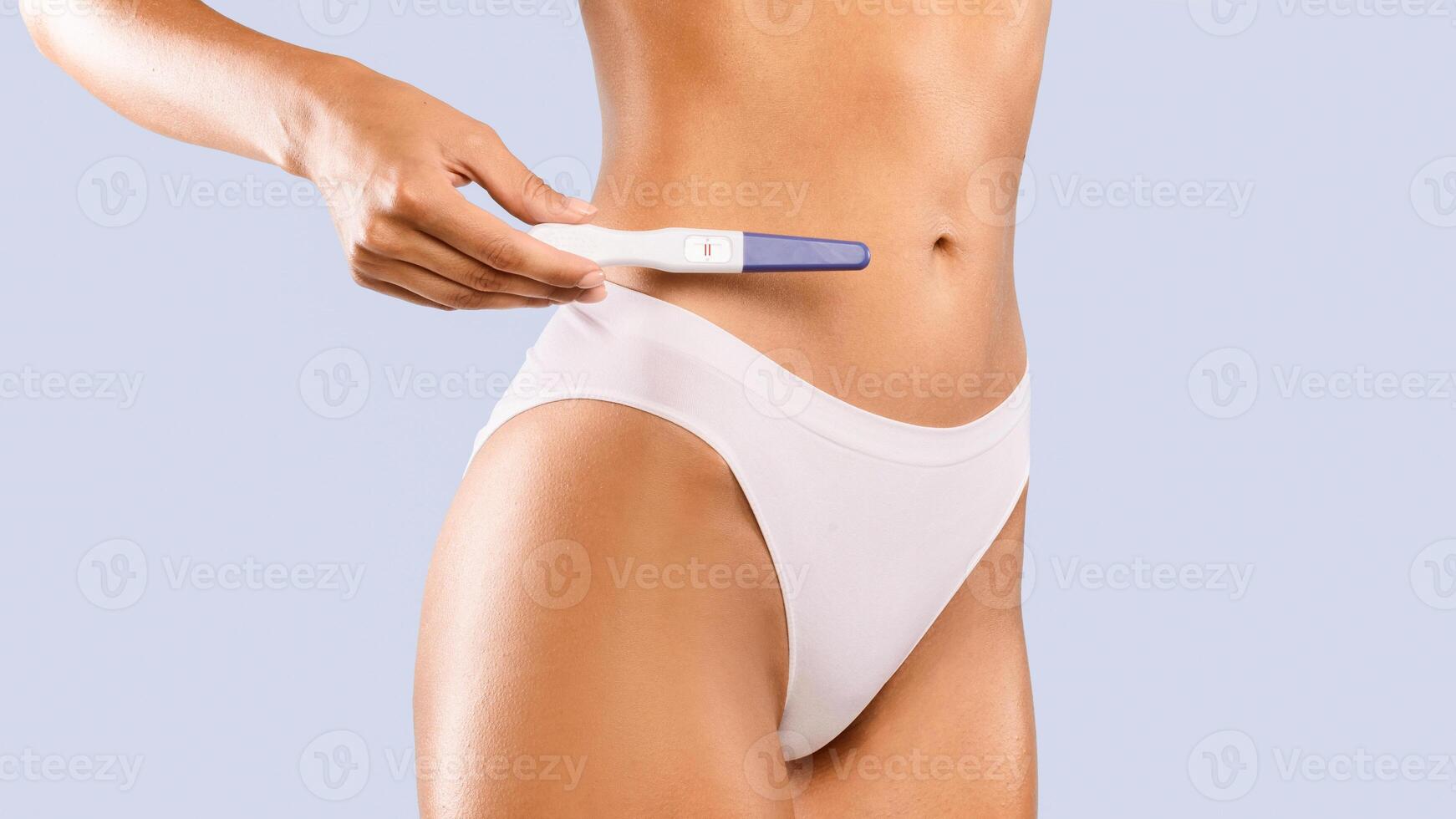 New Life Concept. Closeup cropped view of unrecognizable pregnant woman in white panties holding positive pregnancy test with 2 two red lines standing isolated on blue studio background, banner photo