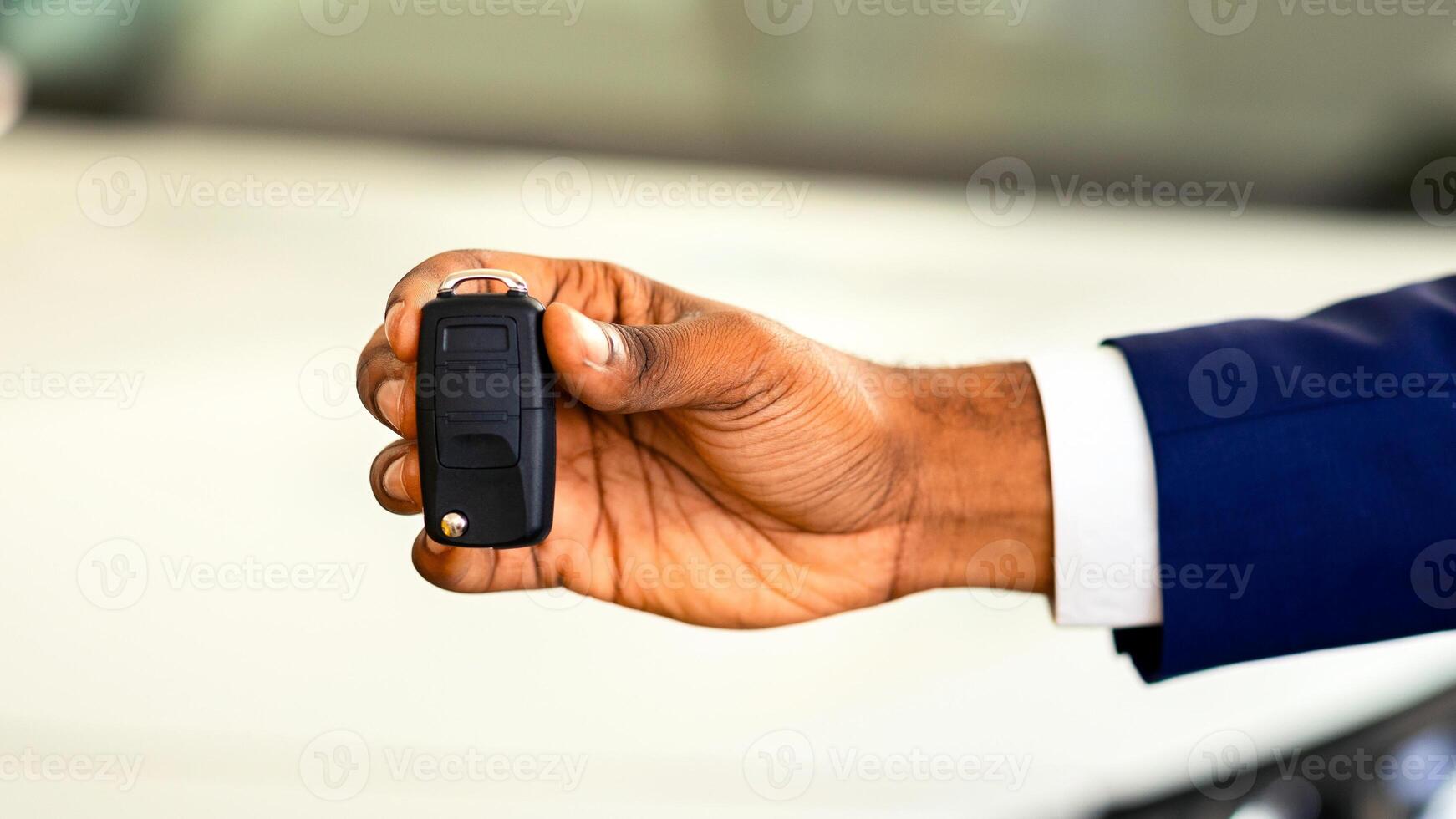 Auto Sale Concept. Closeup Of Car Keys In African American Man Hand, Unrecognizable Black Male Dealership Center Manager In Suit Holding Automobile Key Over Luxury Vehicle On Background, Cropped photo