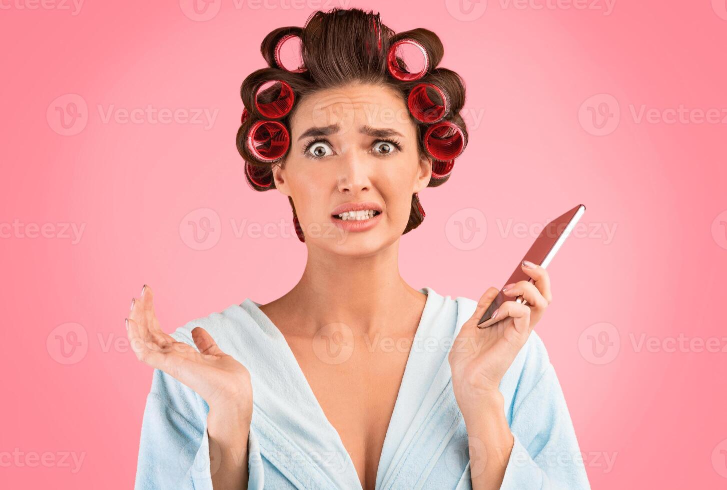 Oops. Confused Housewife Holding Cellphone Making Helpless Gesture Posing Over Yellow Background. Studio Shot photo