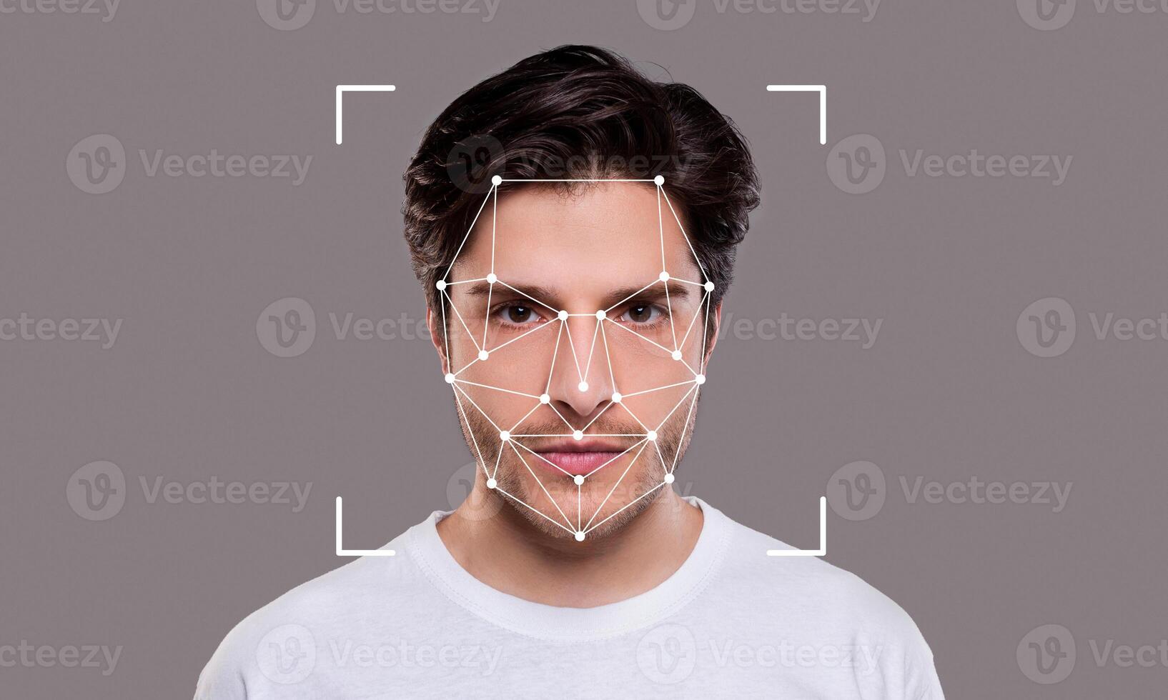 A young man poses against a neutral background while facial recognition technology is applied. The highlights of his facial features are outlined with points and lines, emphasizing identification. photo