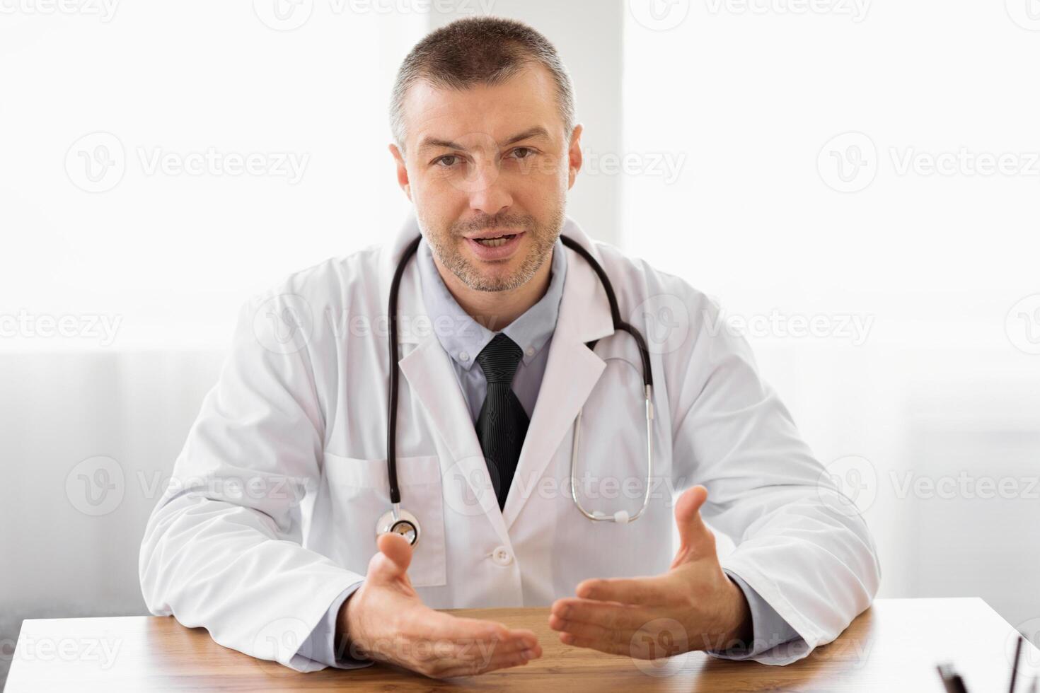 Hospital Visit Concept. Confident middle aged general practitioner speaking in front of the camera photo