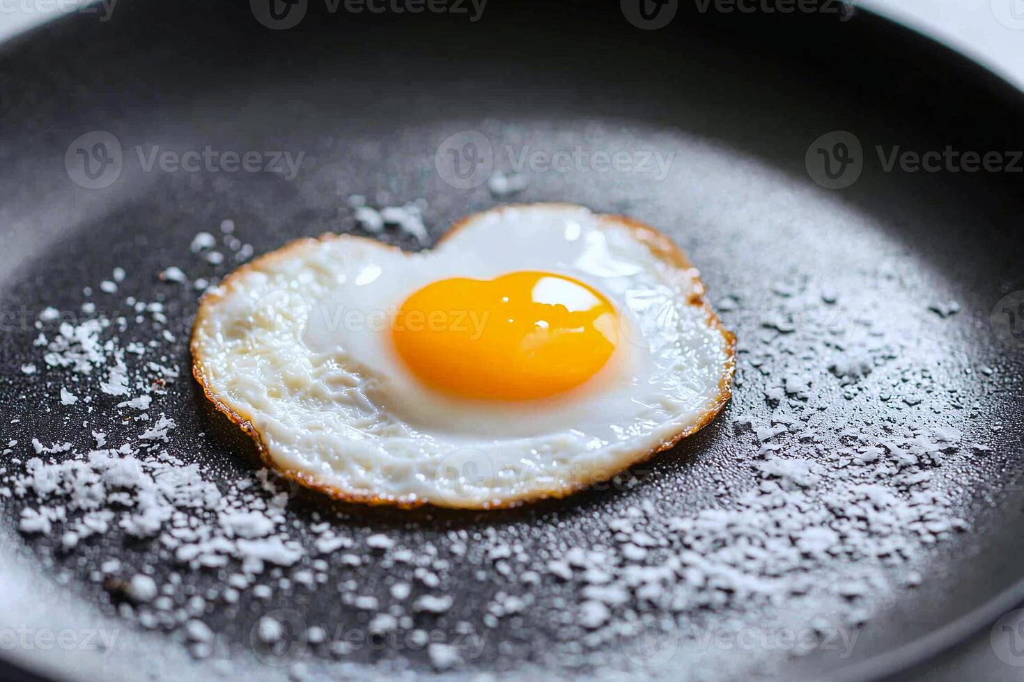 A cracked organic egg with a heart shaped yolk on a frying pan, symbolizing love for healthy eating photo