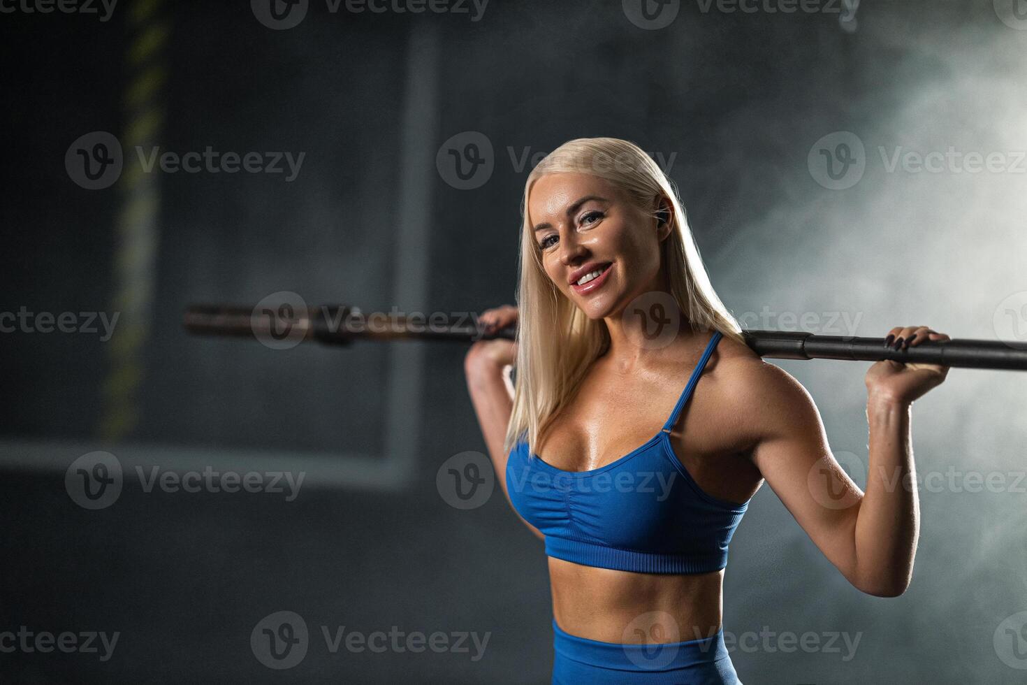 dedicated girl athlete engages in strength training loaded barbell resting on her shoulders. She showcases determination in well lit gym environment during afternoon workout photo