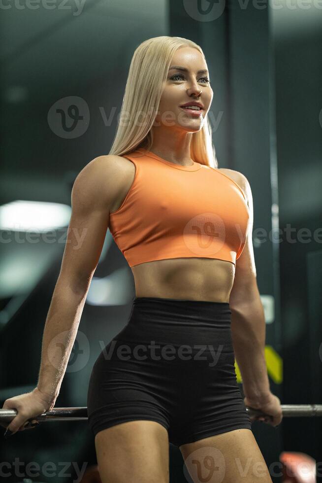 girl athlete showcases her strength and dedication while performing exercise in gym. bright lighting highlights her focus and determination emphasizing her athletic build and form photo