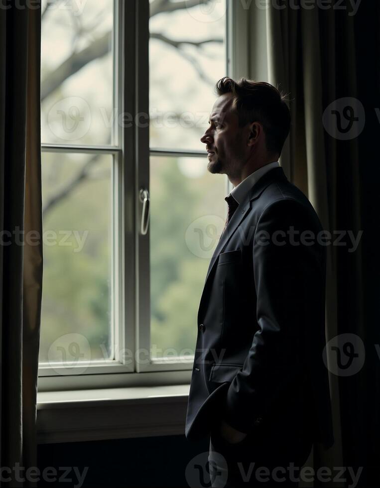 Contemplative businessman gazing out window in dimly lit room for reflective mood design photo