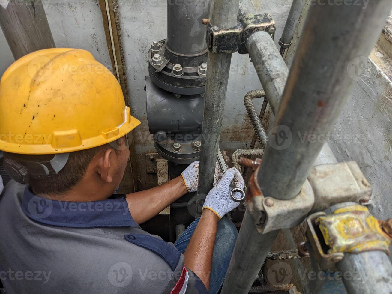 Worker inspecting a valve on a pipe photo
