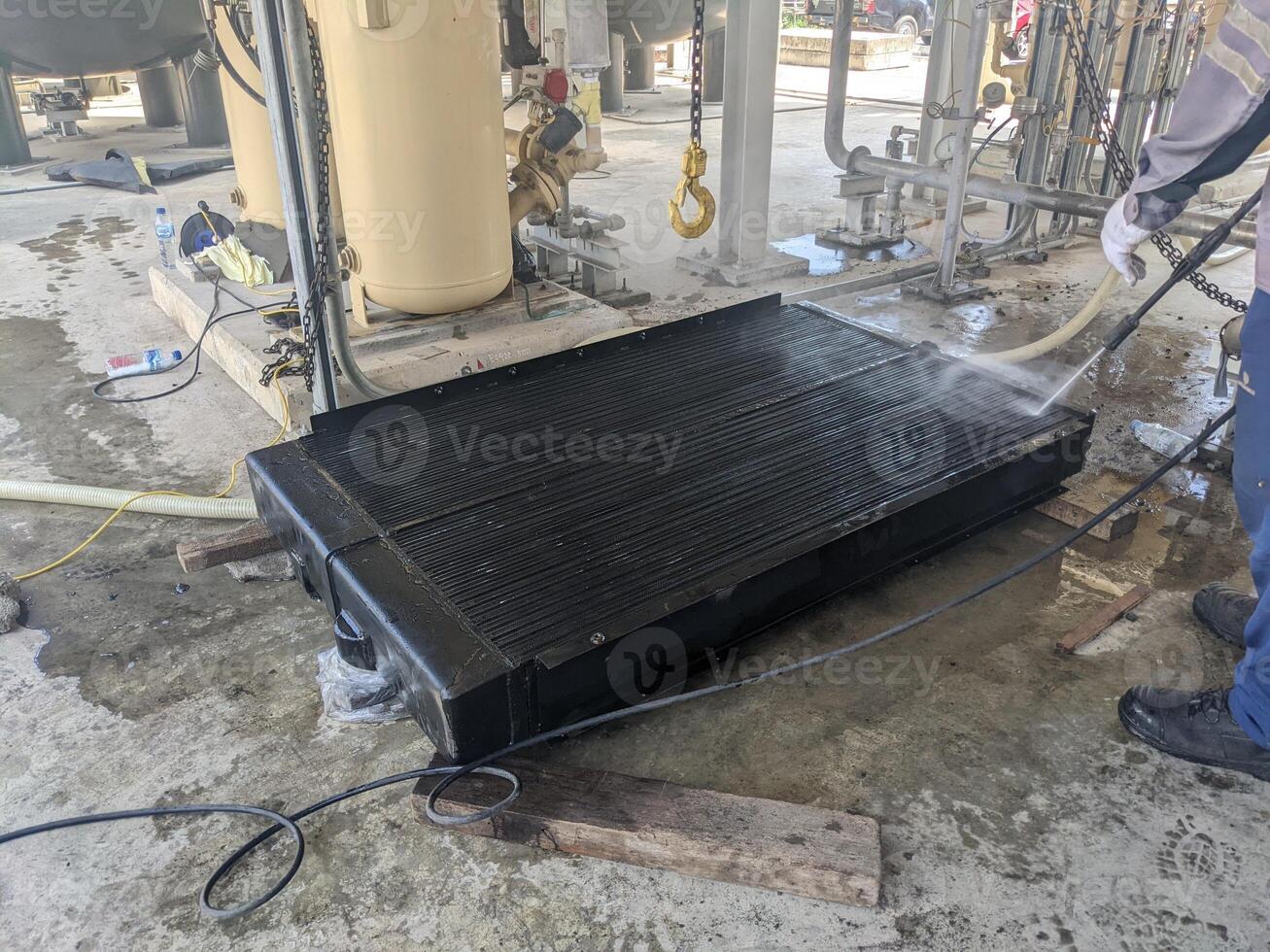 Industrial Cleaning A worker using a pressure washer to clean a large radiator. photo