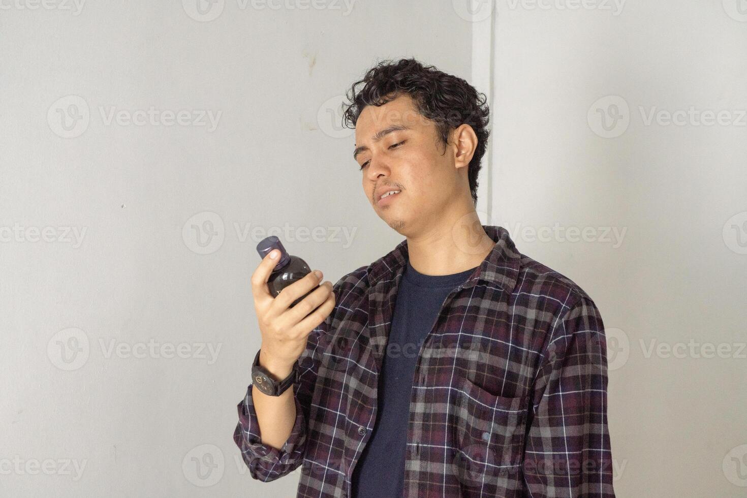 Young Man Examining a Small Bottle photo