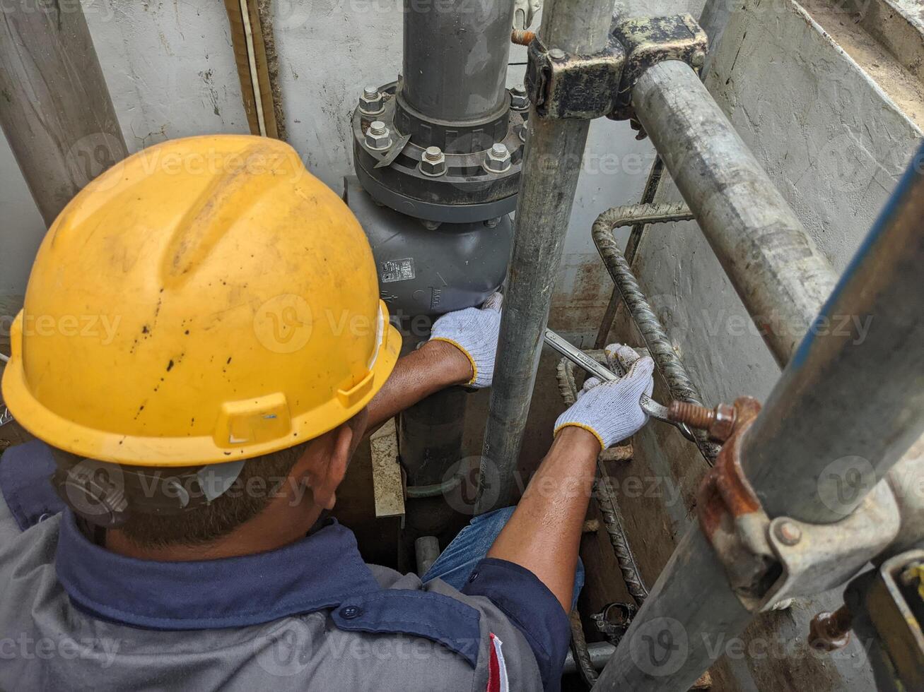 Construction Worker in a Hard Hat Fixing Pipes photo
