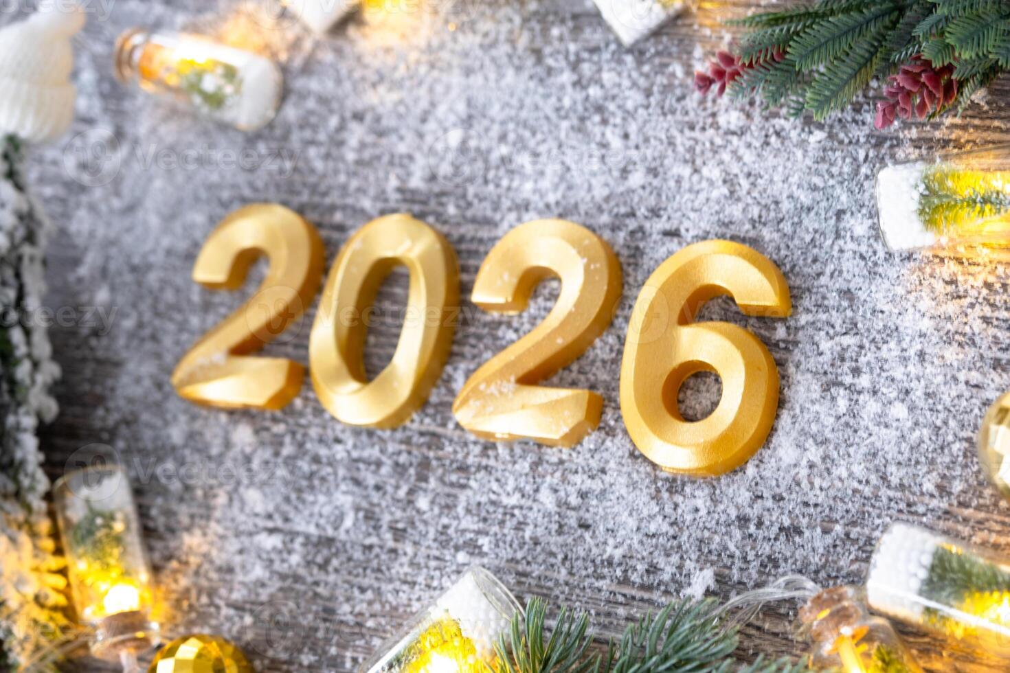 Happy New Year golden numbers 2026 cozy festive grey wooden background with Christmas tree, snow, lights of garlands. Greetings, postcard. Calendar, photo