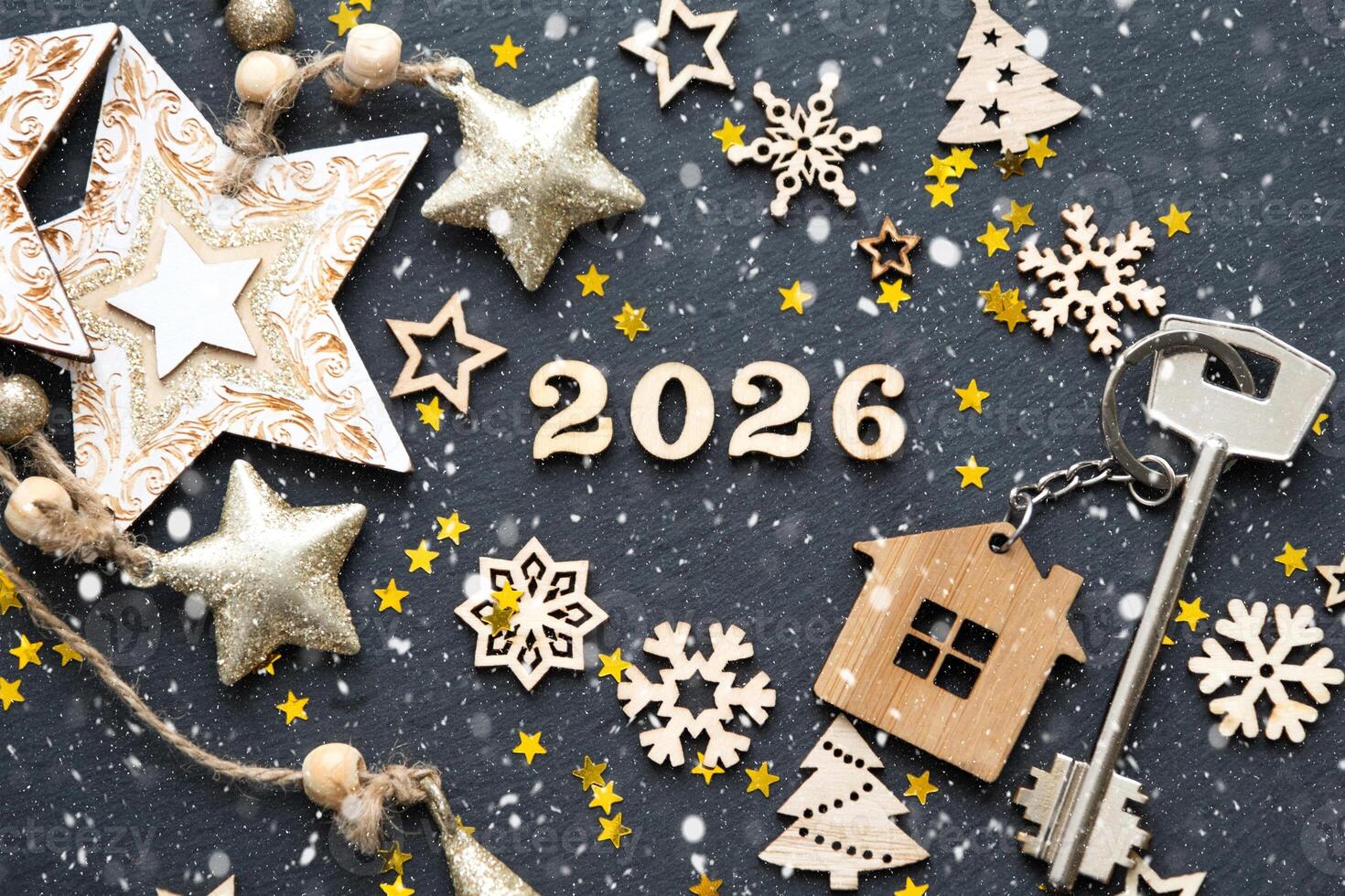 House key with keychain cottage on black background with stars, lights of garlands. New Year 2026 wooden letters, greeting card. Purchase, construction, relocation, mortgage, insurance photo