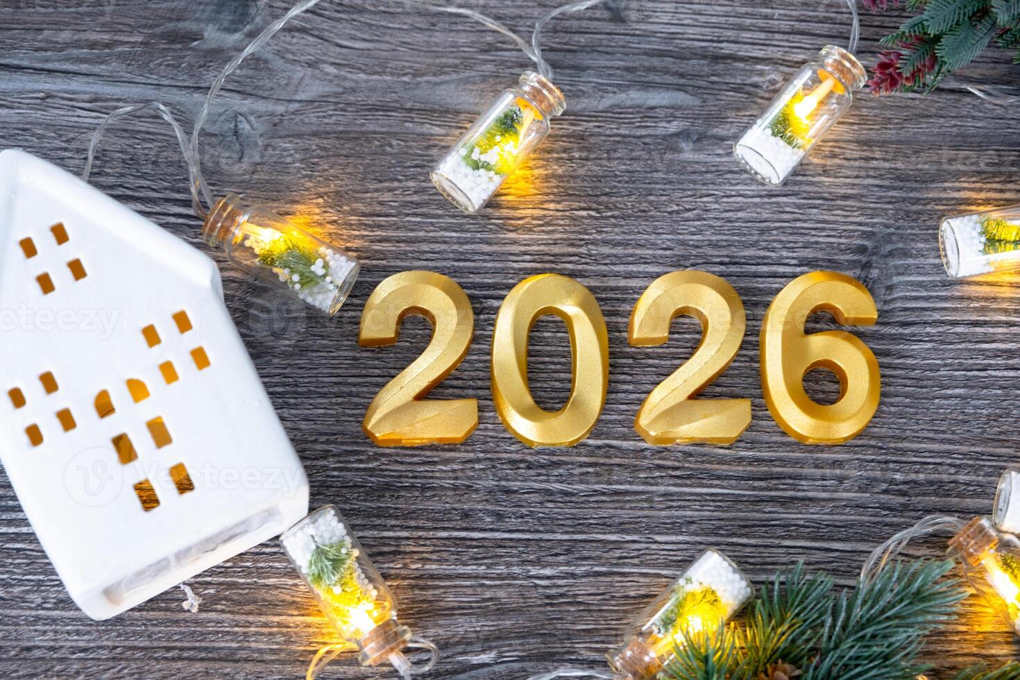 New Year 2026 numbers House key form home on festive grey wooden background flatlay, lights of garlands, greeting card. Housing, real estate, relocation, mortgage, insurance photo