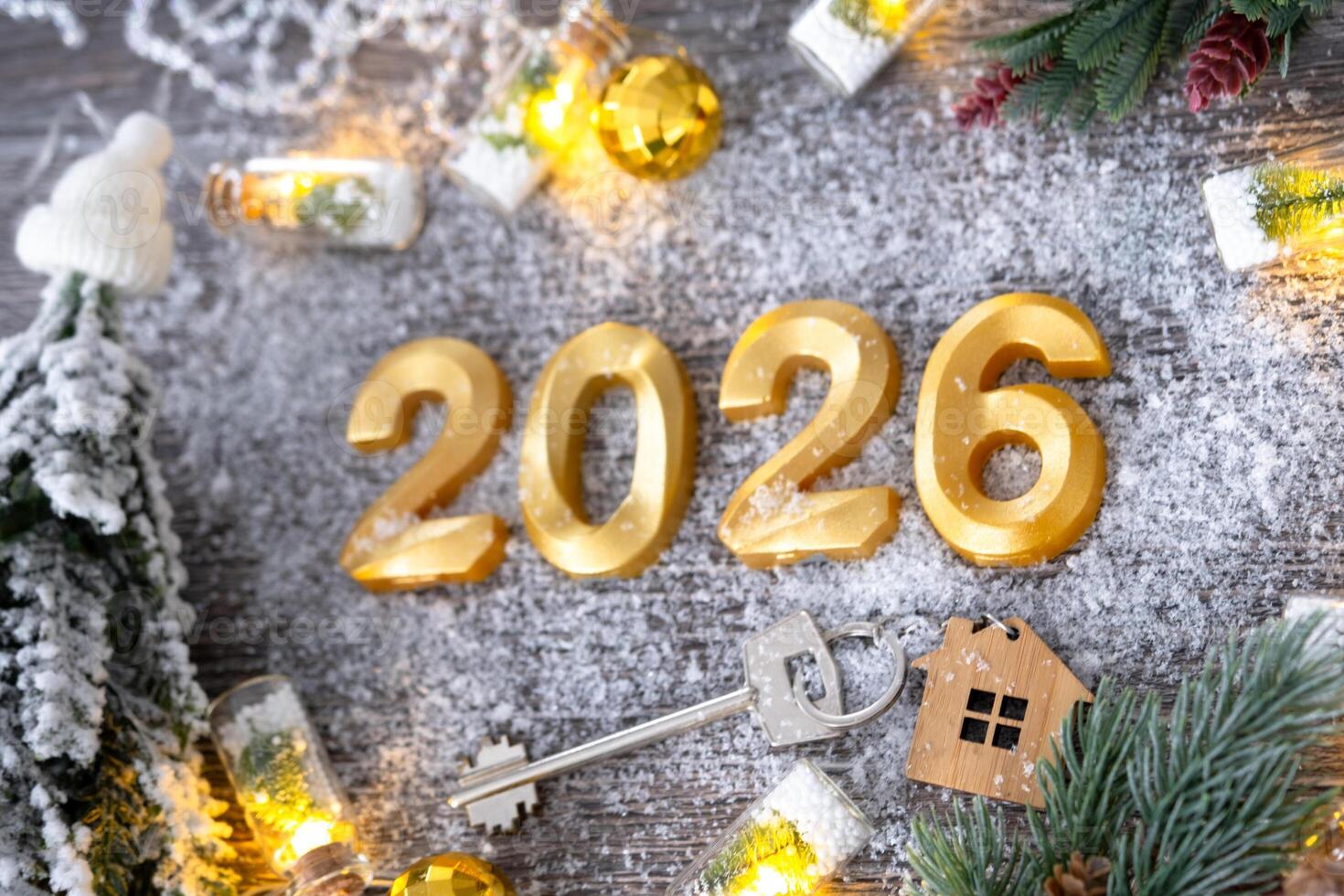 New Year 2026 golden numbers and House key with tiny form of home on festive grey wooden background flatlay, lights of garlands, greeting card. Housing, real estate, relocation, mortgage, insurance1 photo