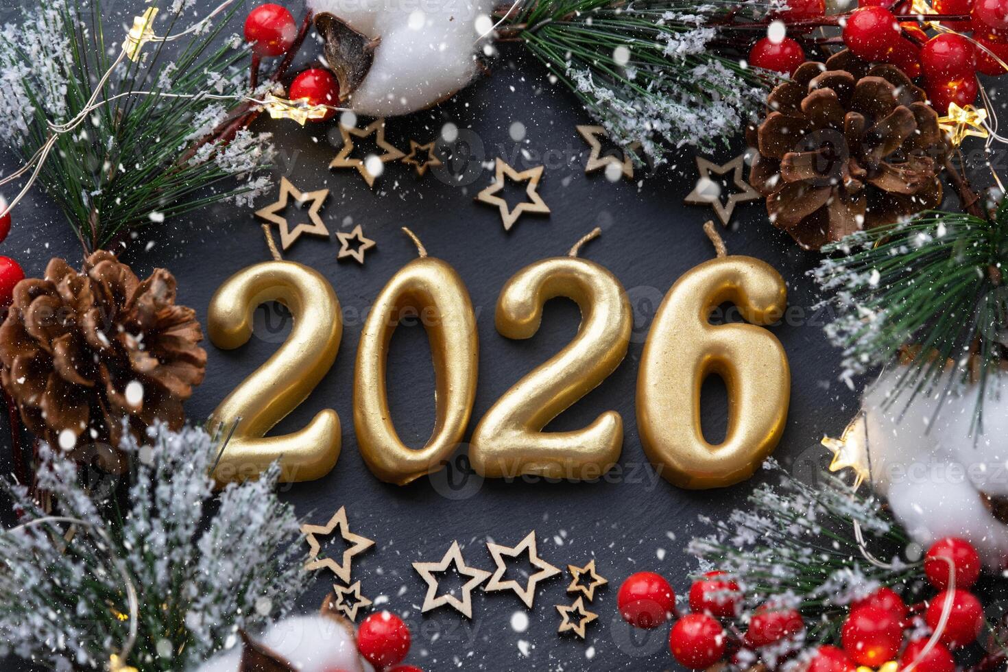 The golden figures 2026 made candles on a black stone slate background are decorated with a festive decor of stars, sequins, fir branches, balls and garlands. Greeting card, happy New Year. photo