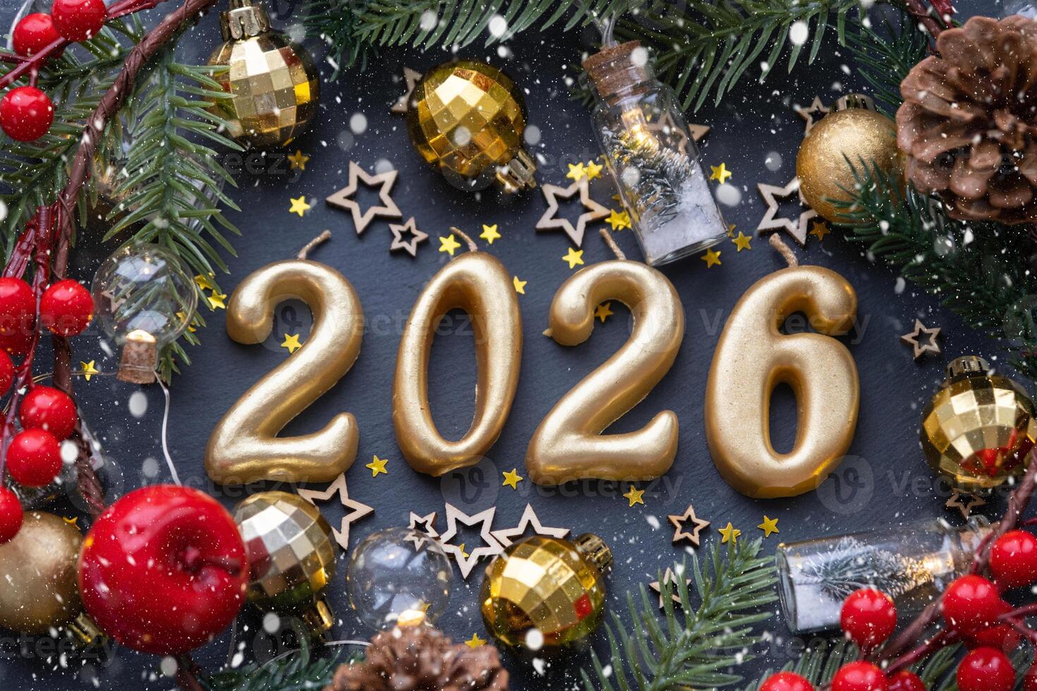 The golden figures 2026 made candles on black stone slate background are decorated with a festive decor of stars, sequins, fir branches, balls and garlands. Greeting card, happy New Year. photo