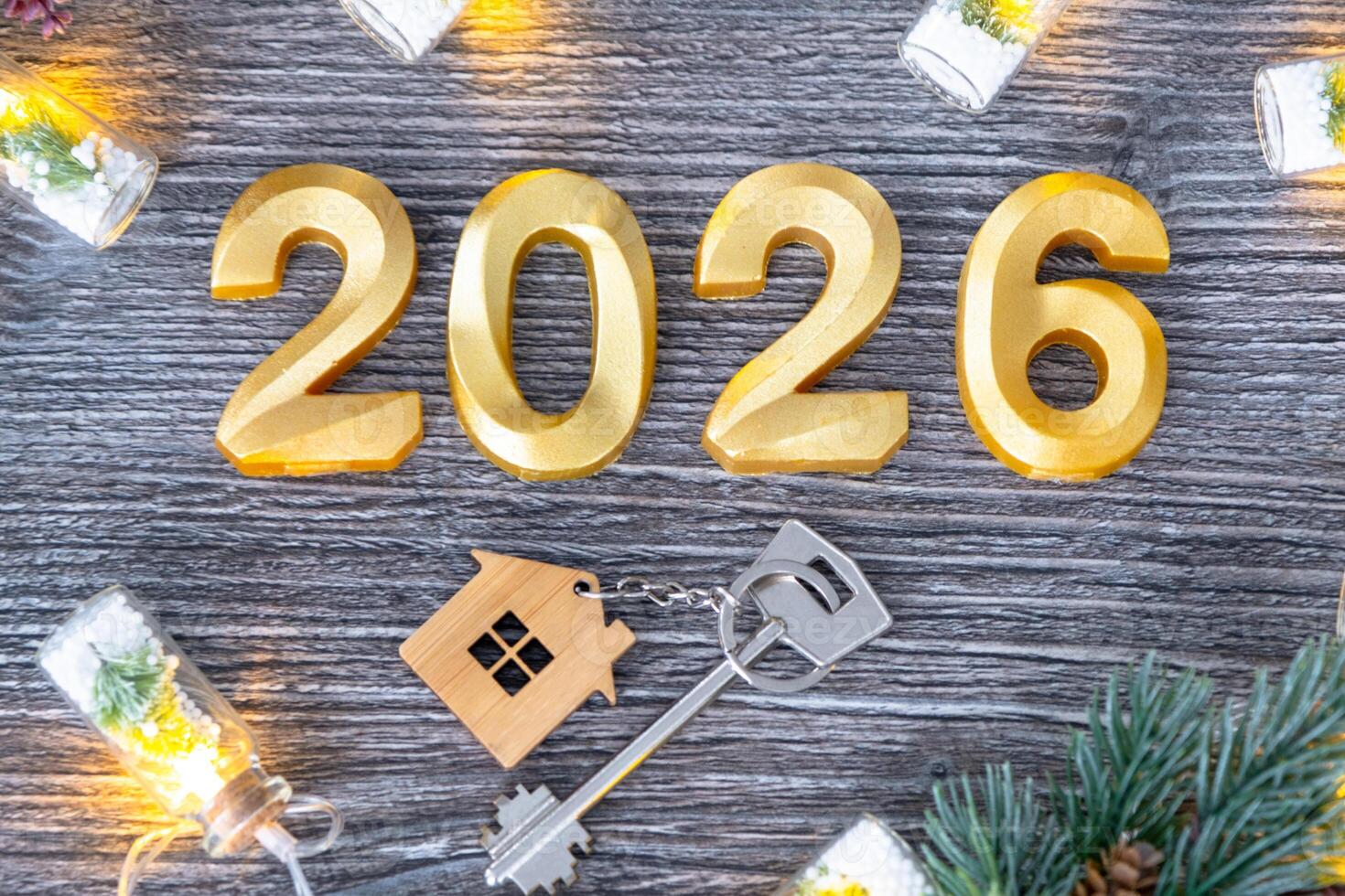 New Year 2026 numbers and House key tiny form of home on festive grey wooden background flatlay, lights of garlands, greeting card. Housing, real estate, relocation, mortgage, insurance photo