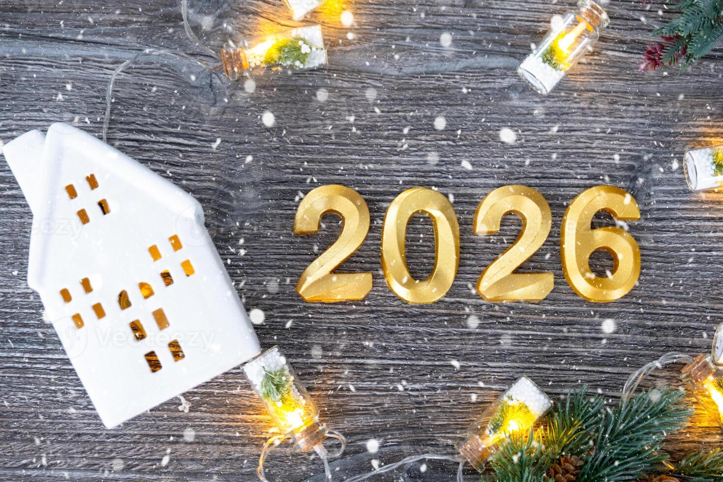 New Year 2026 golden numbers and House key tiny form of home on festive grey wooden background flatlay, lights of garlands, greeting card. Housing, real estate, relocation, mortgage, insurance photo