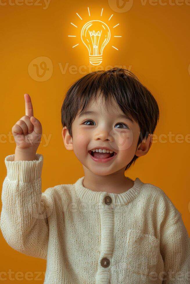 A little boy is holding up his finger with an idea light bulb above his head photo