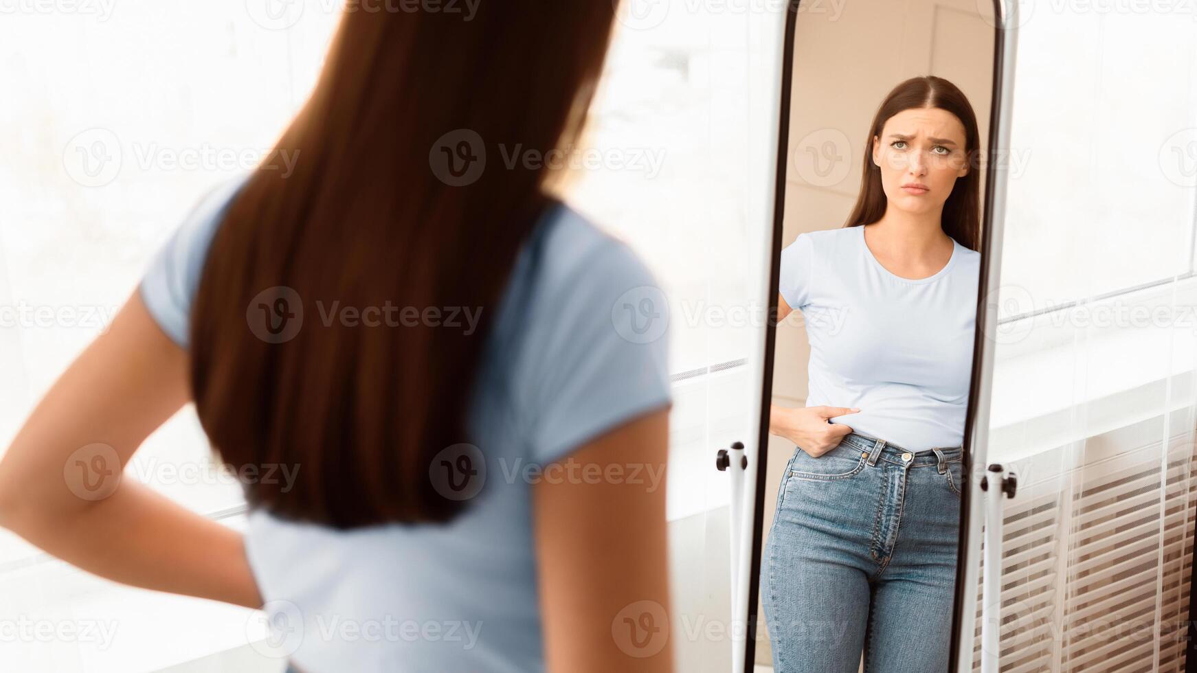 Weight Gain. Upset Woman Touching Fat Belly Looking In Mirror Indoor, Struggling To Lose Weight. Selective Focus, Panorama photo