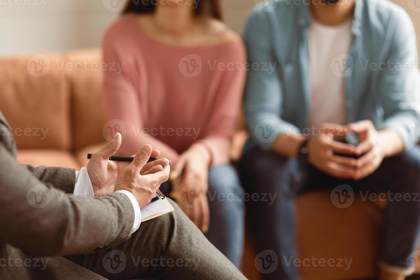 Help Concept. Closeup Cropped View Of Man Counselor Therapist Or Consultant In Suit Talking With Couple Sitting In Office, Giving Professional Advice. Selective Focus On Hands With Clipboard And Pen photo