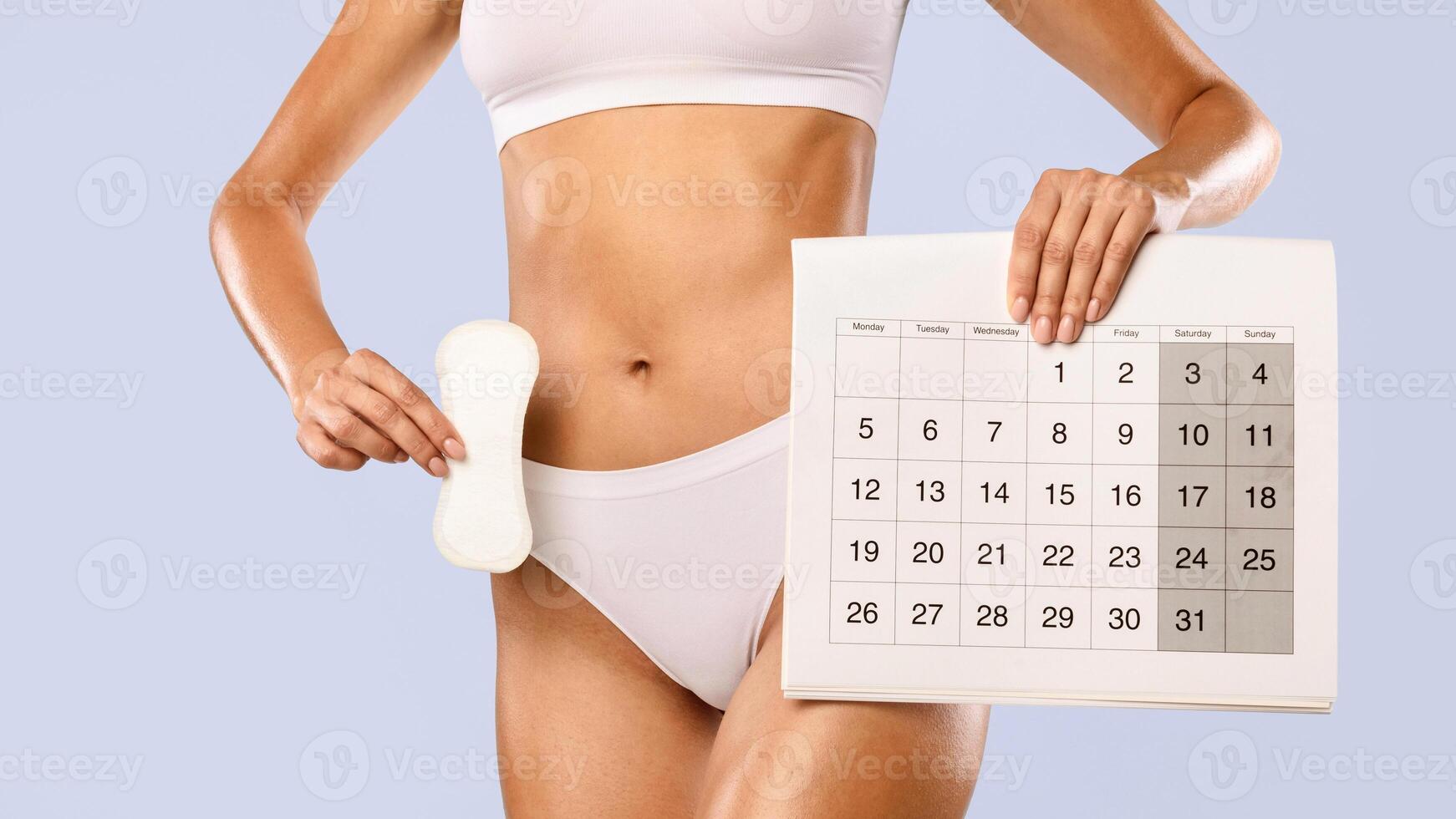 Period And Female Hygiene Protection. Closeup cropped view of unrecognizable woman in white underwear holding menstrual pad and paper calendar isolated on blue studio background, banner photo