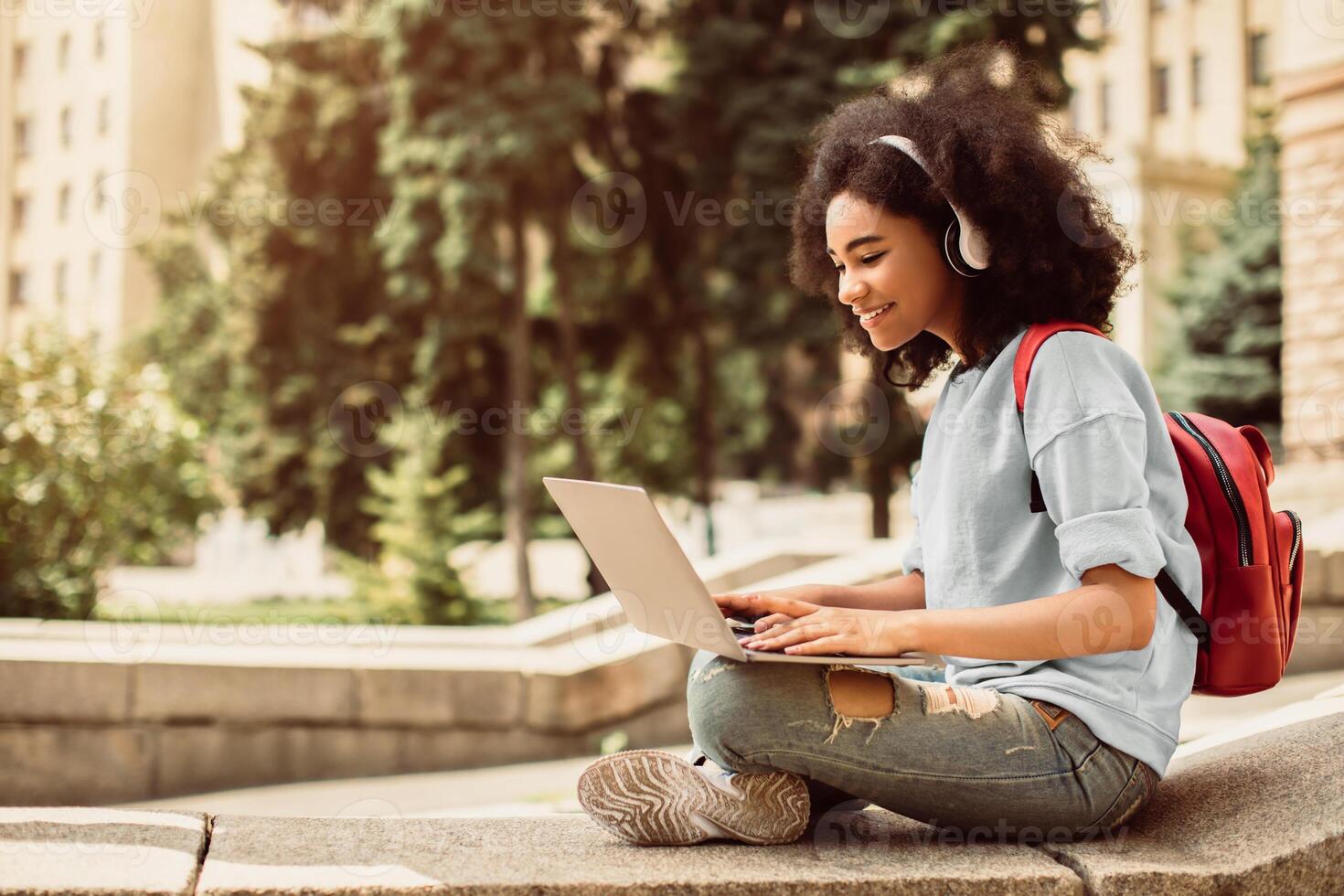 E-Learning. African American Female Student Using Laptop Learning Sitting Near University Building Outdoor. College Education And Modern Study, Educational Gadgets And Computers Concept photo