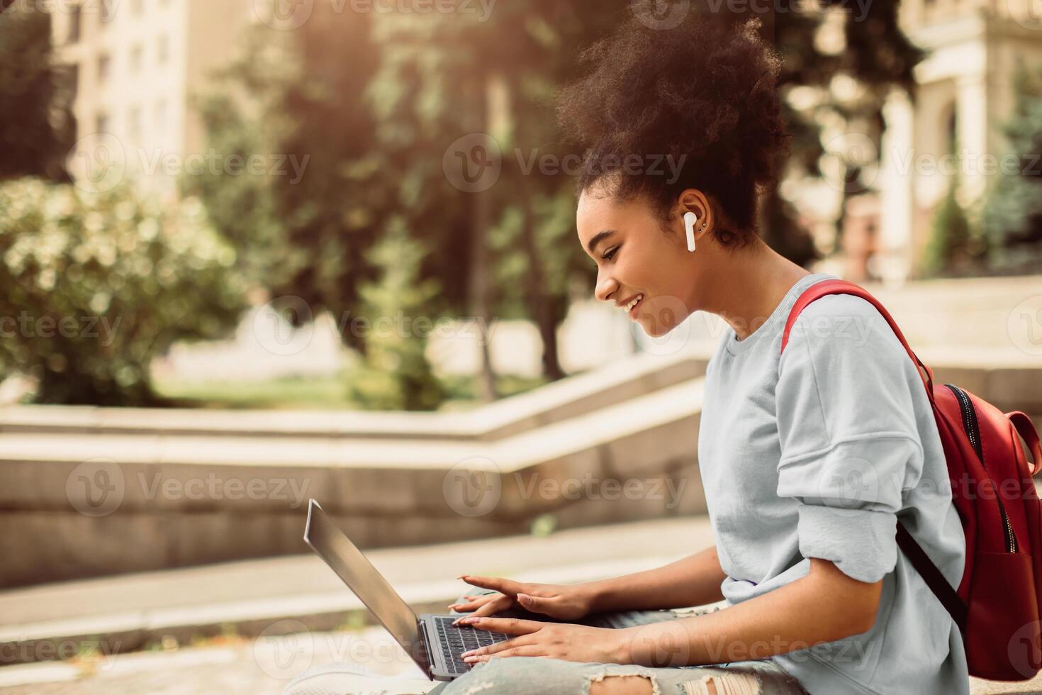 Distance Learning. Happy African American Student Browsing Internet On Laptop Having Remote Lecture Sitting Outdoors. College Girl Using Computer. E-Learning, People And Gadgets photo