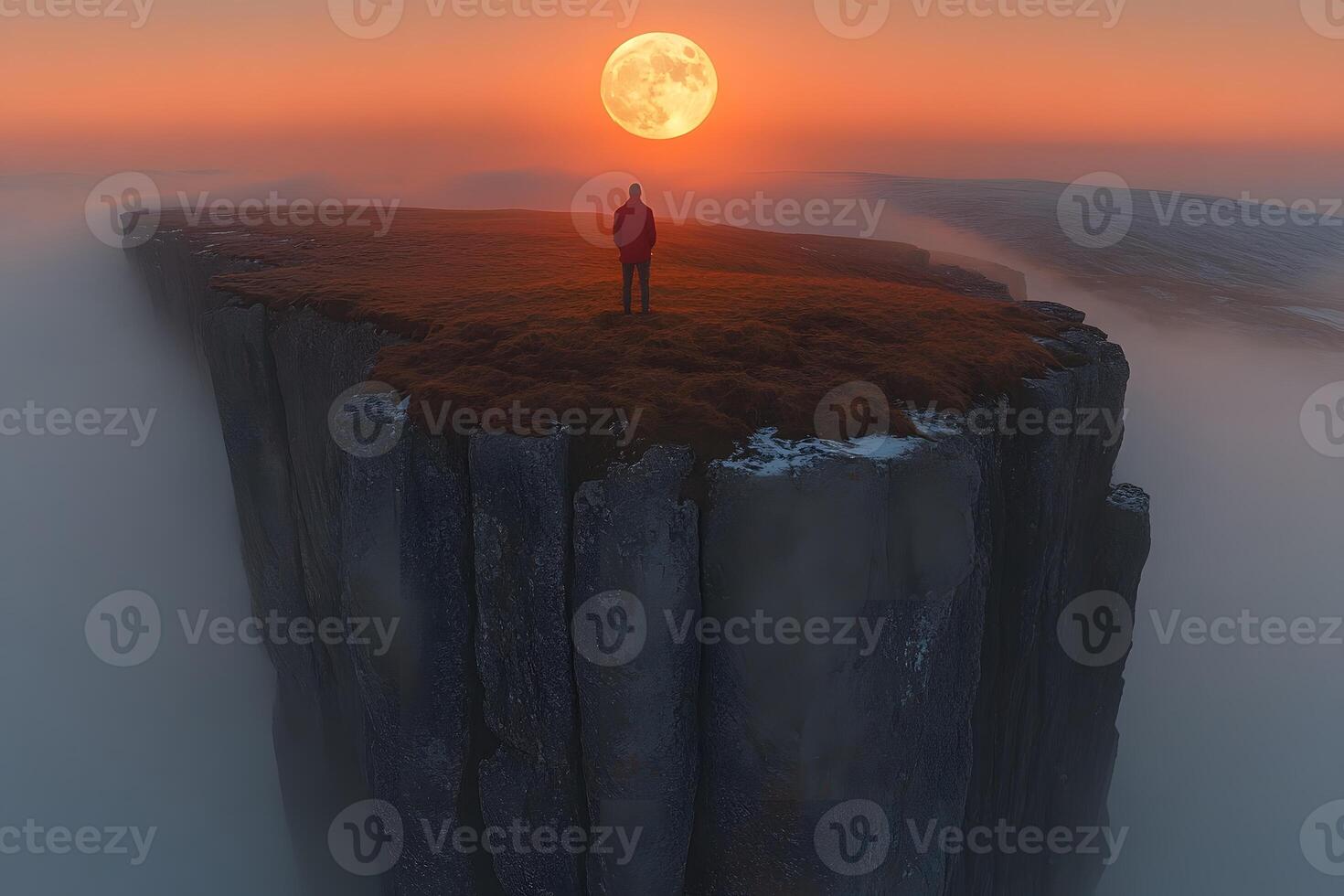 Solitary Figure on Cliff at Dusk with Full Moon for Inspirational and Adventure Themes photo