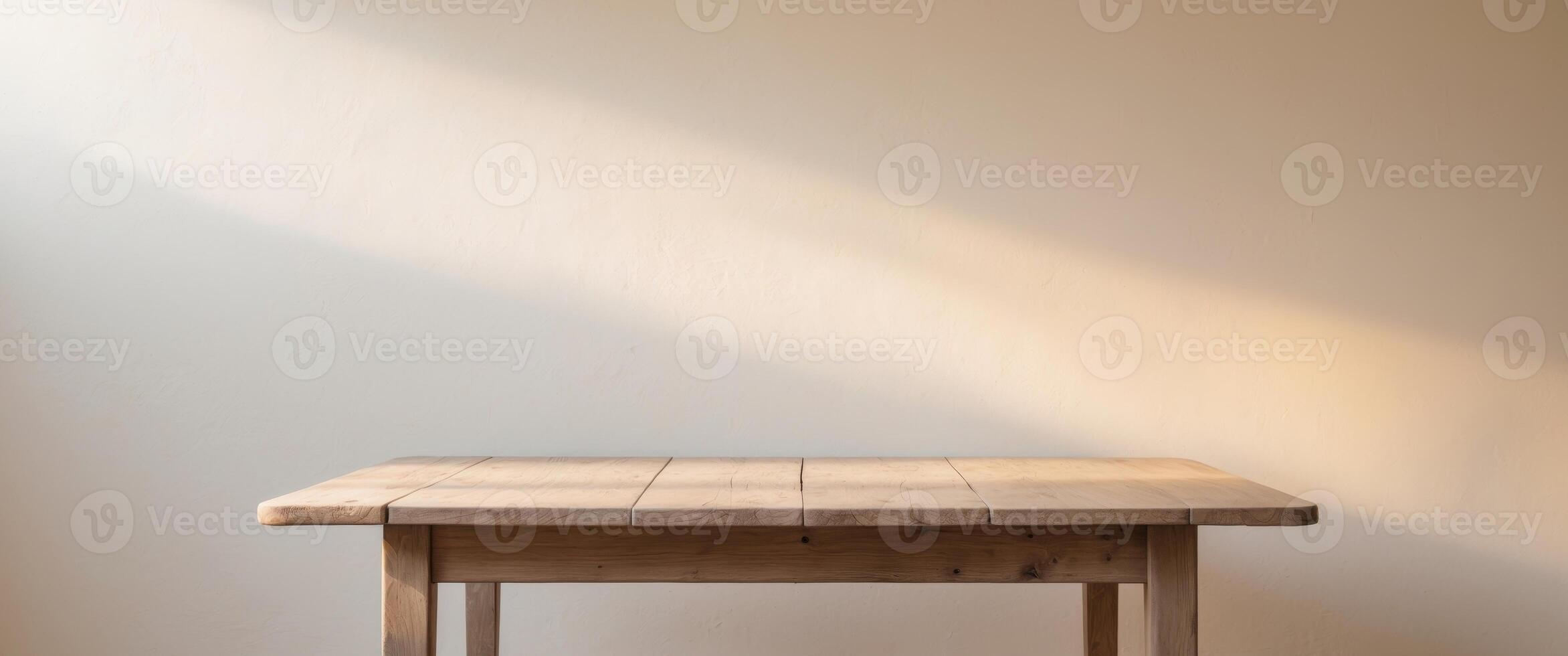 a simple wooden table with soft sunlight hitting the white wall in the background photo