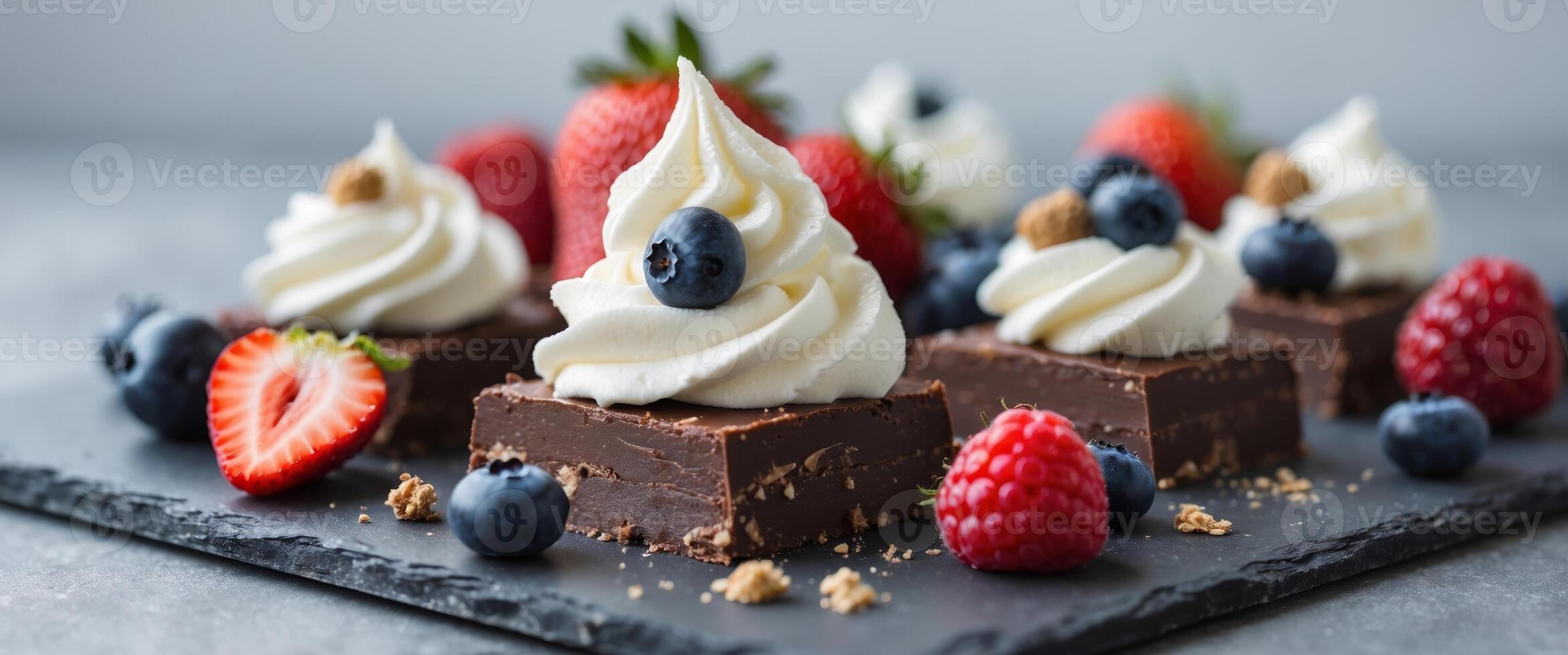 Decadent Chocolate Fudge Squares Garnished with Fresh Berries and Creamy Whipped Topping on a Dark Slate Surface. photo