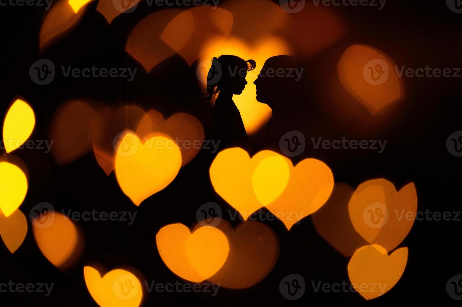 A heart-shaped bokeh and silhouettes of two people in it. photo