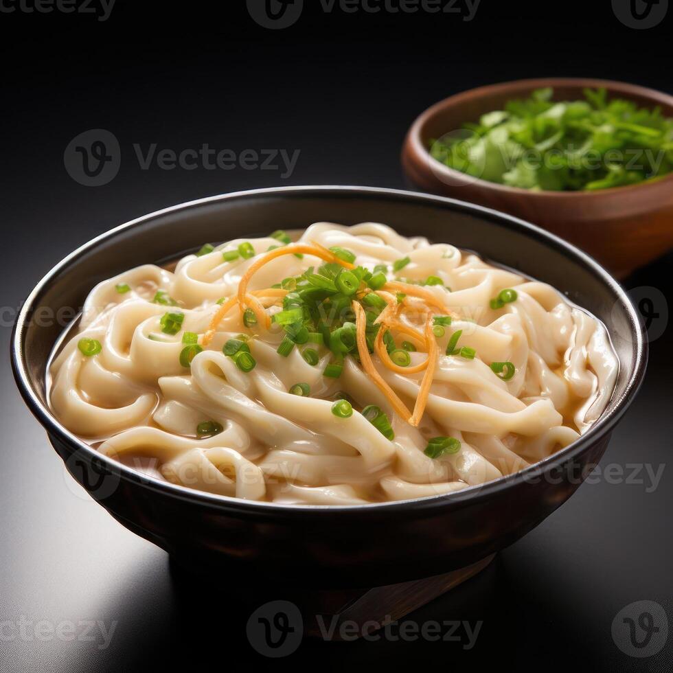 A bowl of udon noodles with broth and garnishes photo