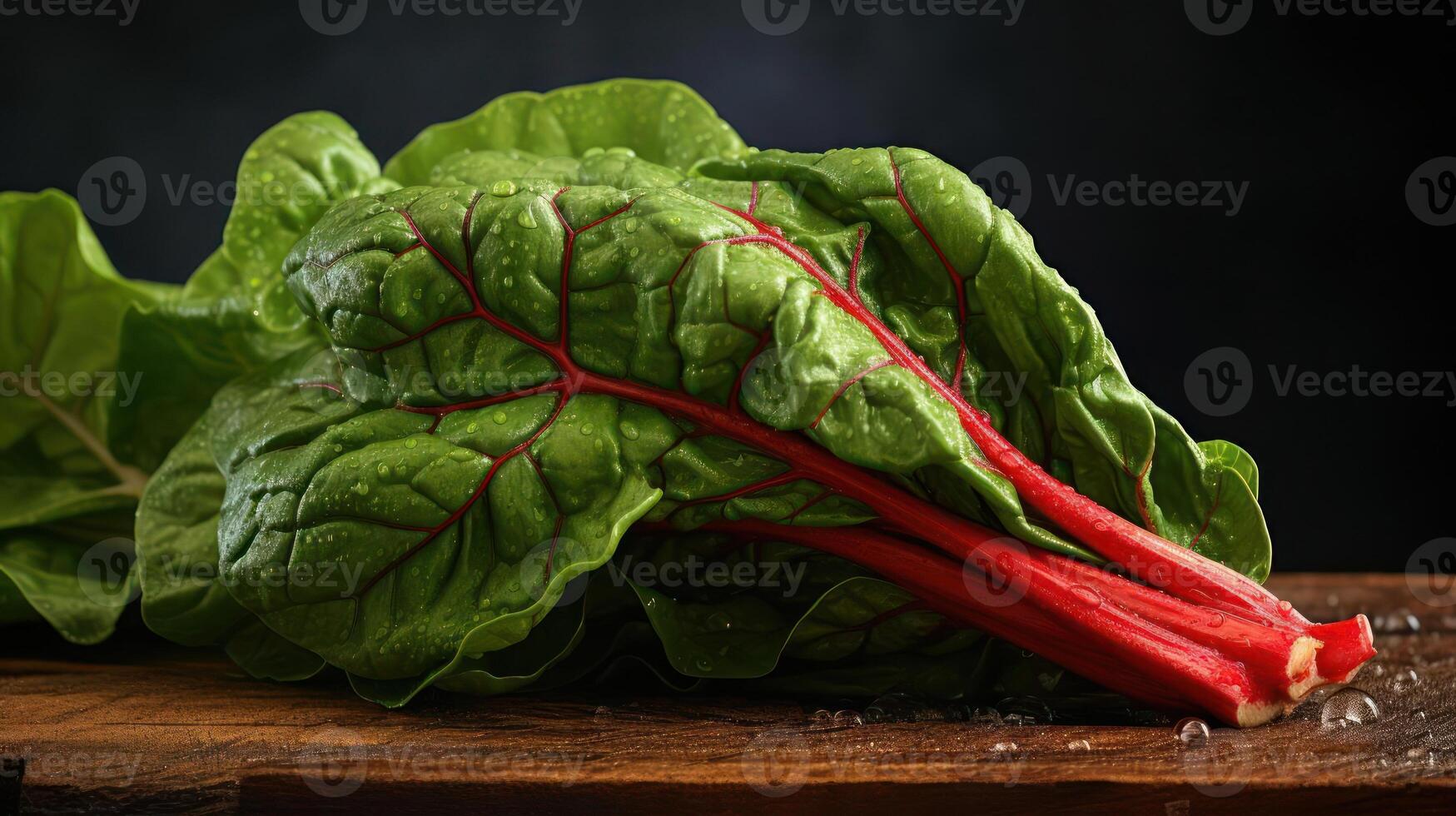 A close-up photograph of a leafy green vegetable with red veins on a wooden table photo