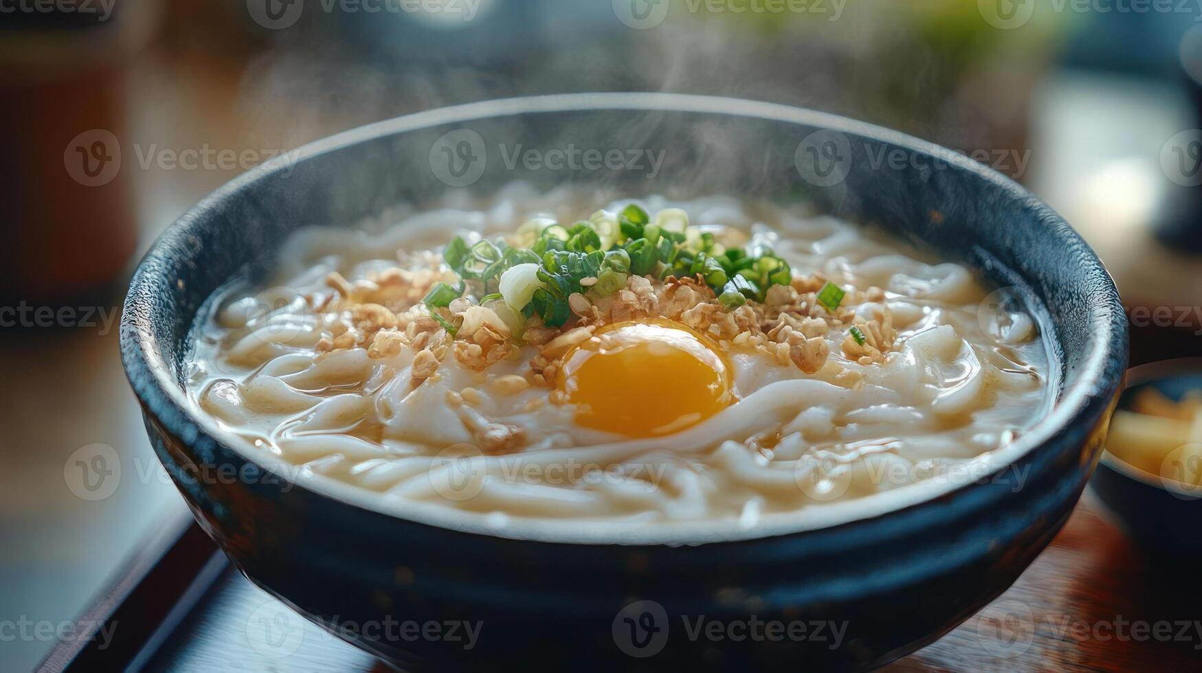 A bowl of steaming hot noodles with an egg and chopped green onions on top photo