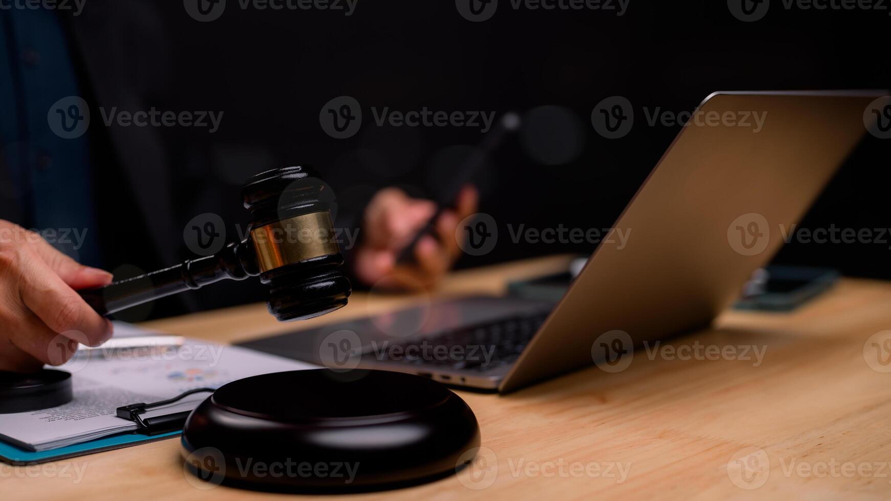Judges gavel is poised over sleek workspace, intersection of traditional justice and modern technology, highlighting how digital tools support legal proceedings in todays world photo