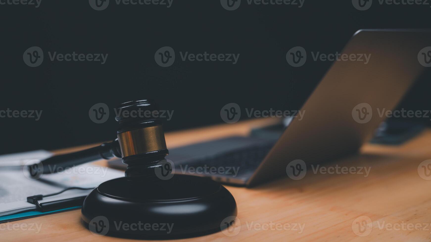 Wooden gavel rests beside laptop on wooden desk, symbolizing intersection of law and technology in modern legal practices photo