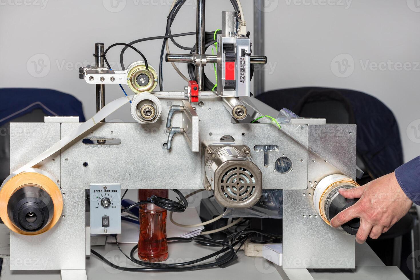 A fitter's hand adjusts a laser print line on self-adhesive drum-wound labels. photo