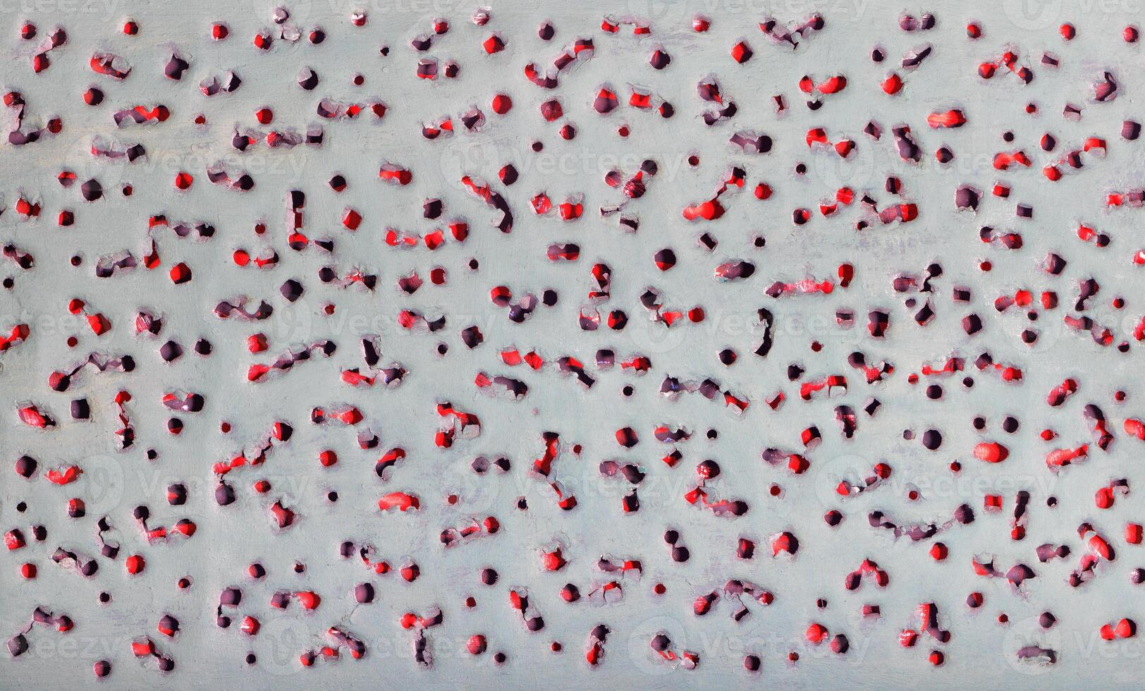 Abstract pattern texture with pierced ragged holes on a gray background on an underlay of red. photo