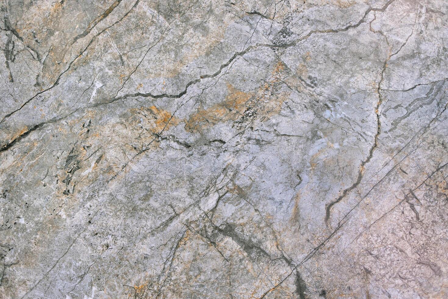 Gray-green polished granite surface with various structural cracks. photo