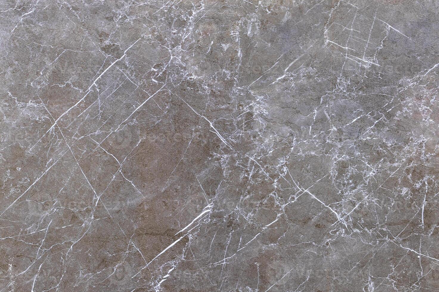 Grey-brown polished granite surface with various cracks. photo